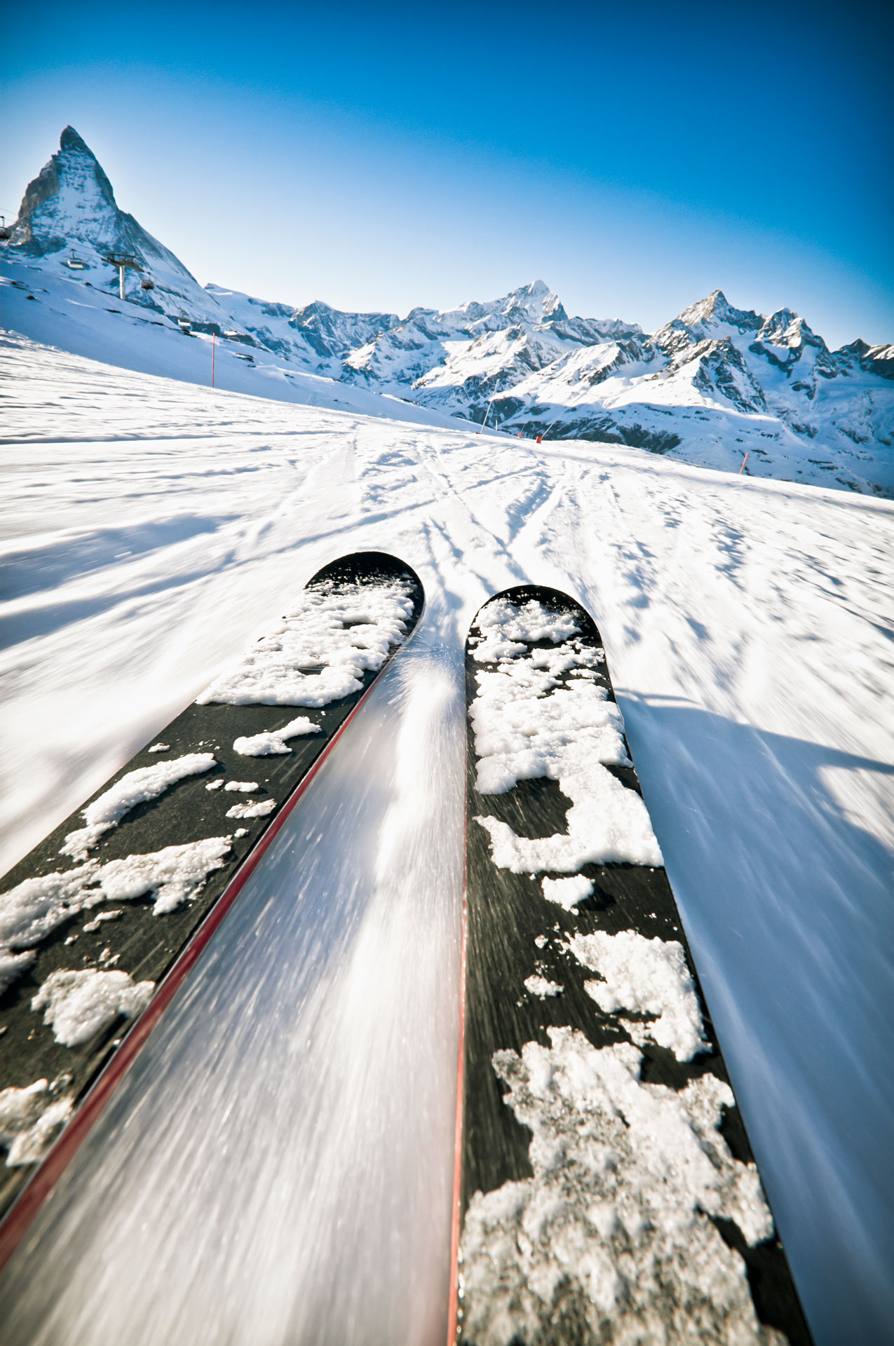 A close up of skis with motion blur from fast movement along a piste