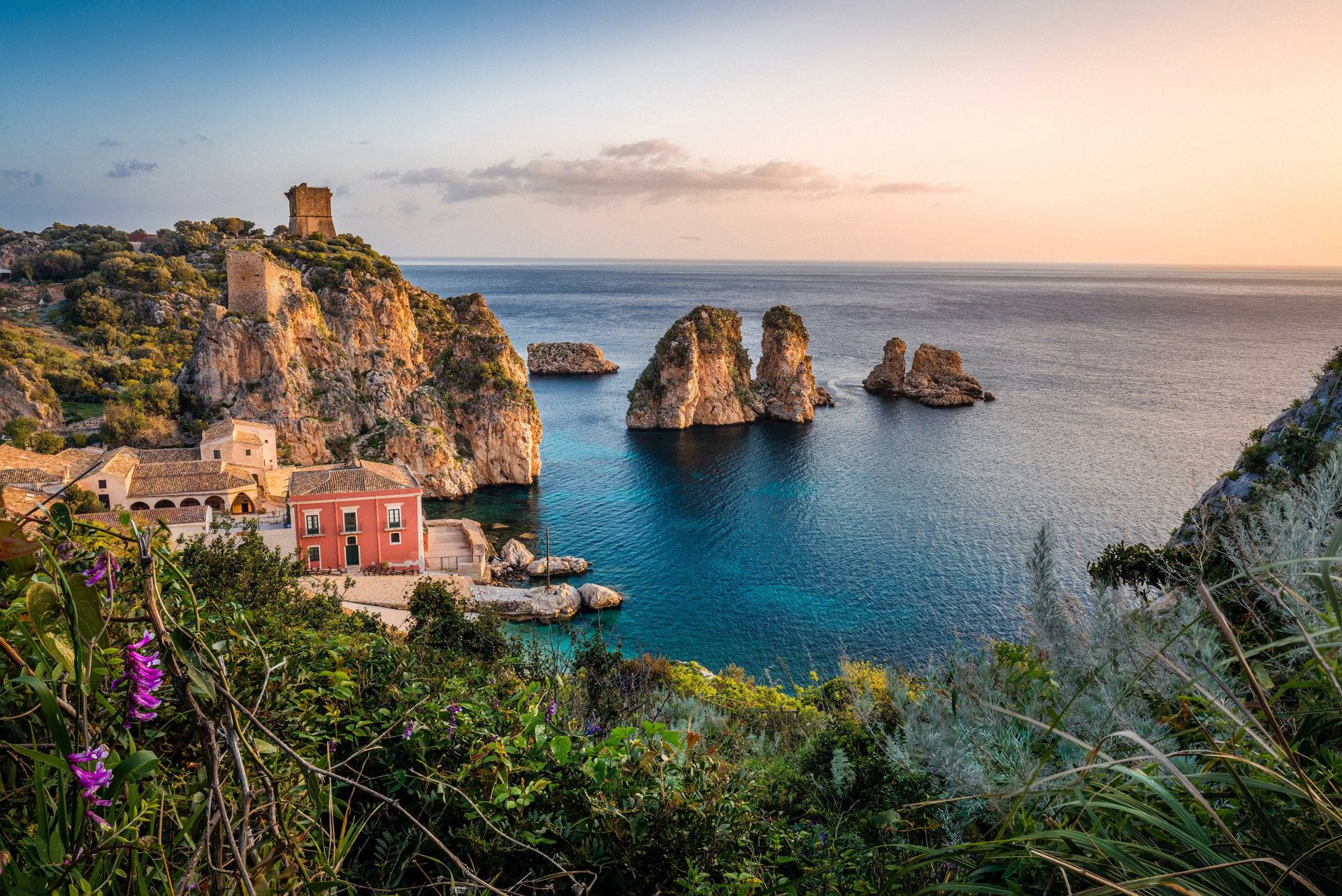 A former fishing house in a rocky beach cove as the sun sets