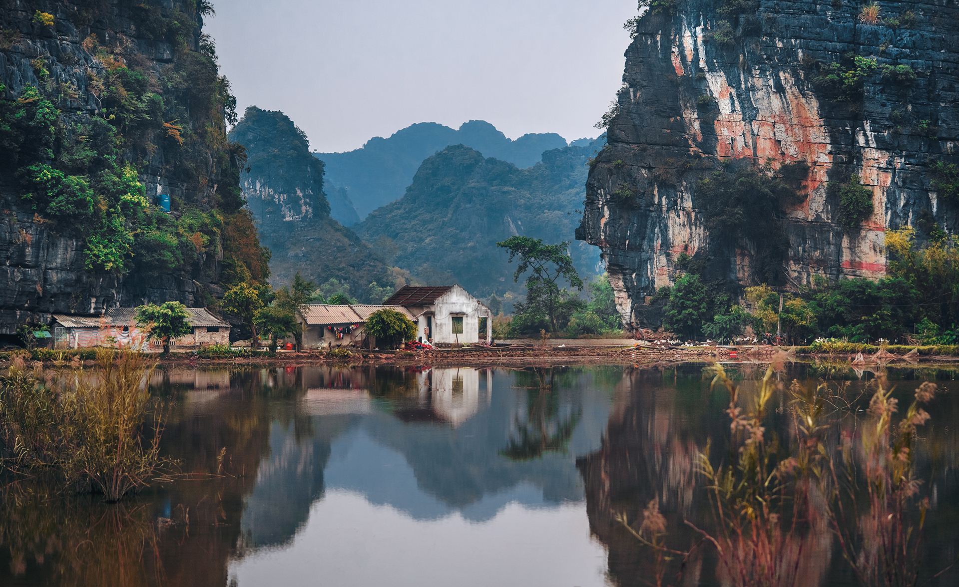 A white house at waters edge between two cliffs
