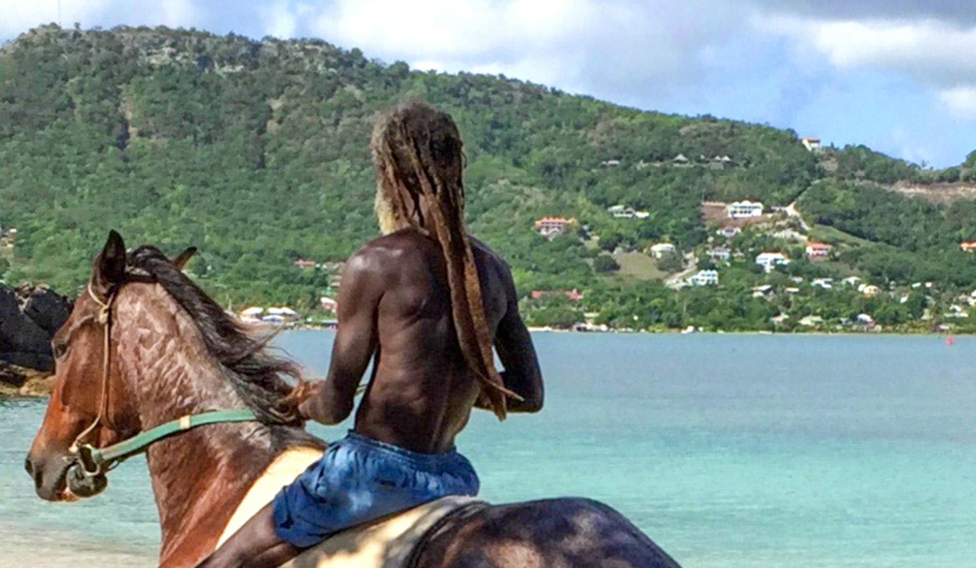 A man on a horse looking across water to another shoreline