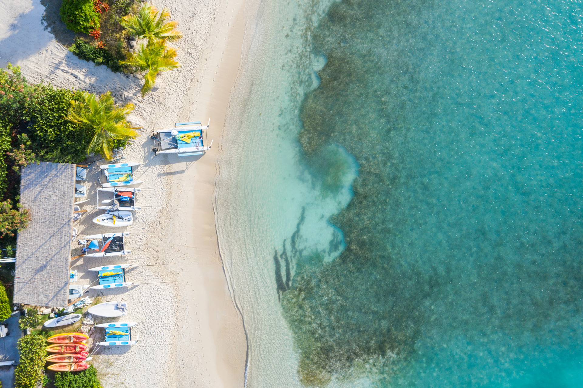 A birds eye view of a beach with chairs and small boats lined up
