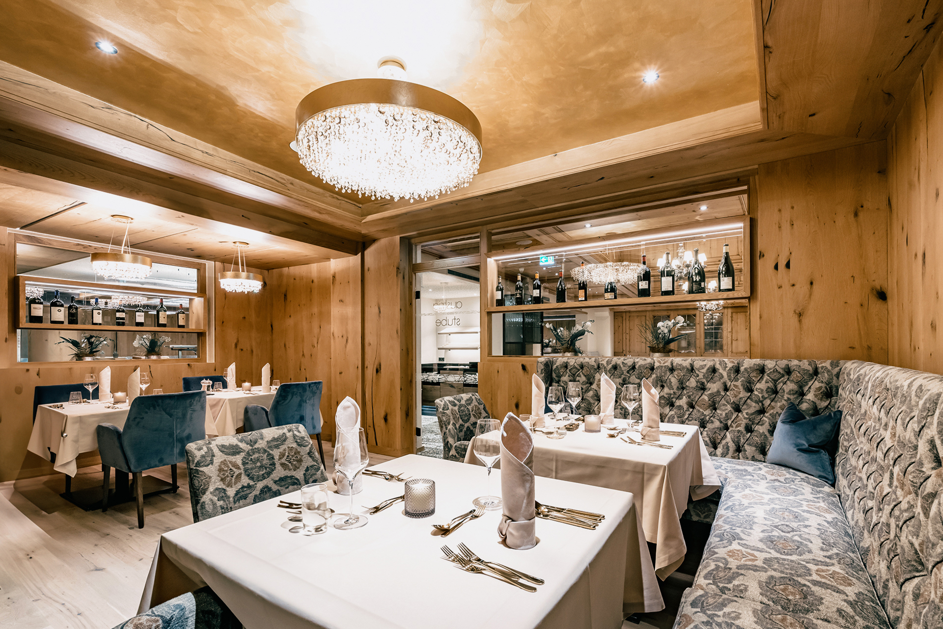 Elegant dining area in Austria Stuben Restaurant at Gourmet and Wine Hotel Austria featuring wooden walls, plush seating, chandeliers, and neatly set tables