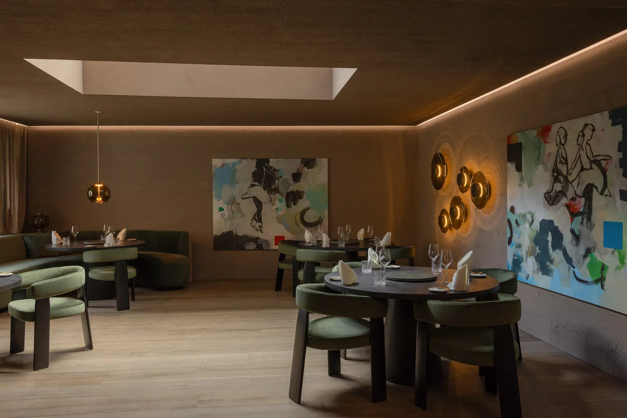 Elegant dining area in Austria Stuben Restaurant at Gourmet and Wine Hotel Austria featuring artwork on the walls, plush seating, moody lighting, and neatly set tables