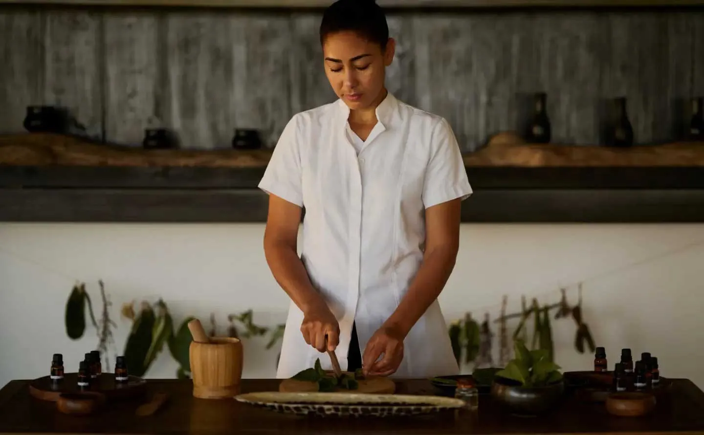 Spa setting at Amanyara with a therapist preparing fresh botanical ingredients for a wellness treatment.