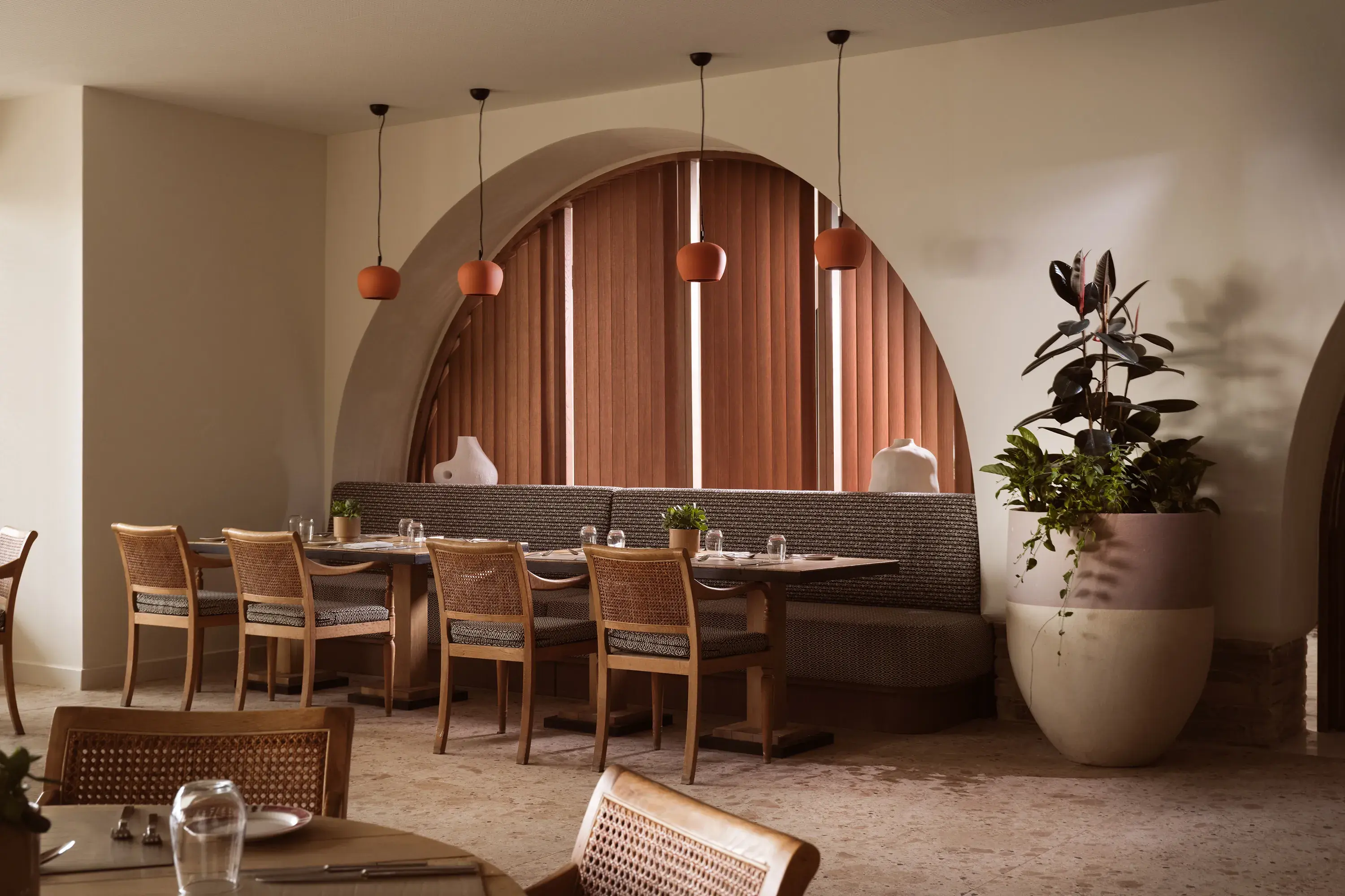 Stylish Melathron Restaurant at Eagles Palace in Greece with warm earthy décor, arched wooden shutters and elegant dining seating.