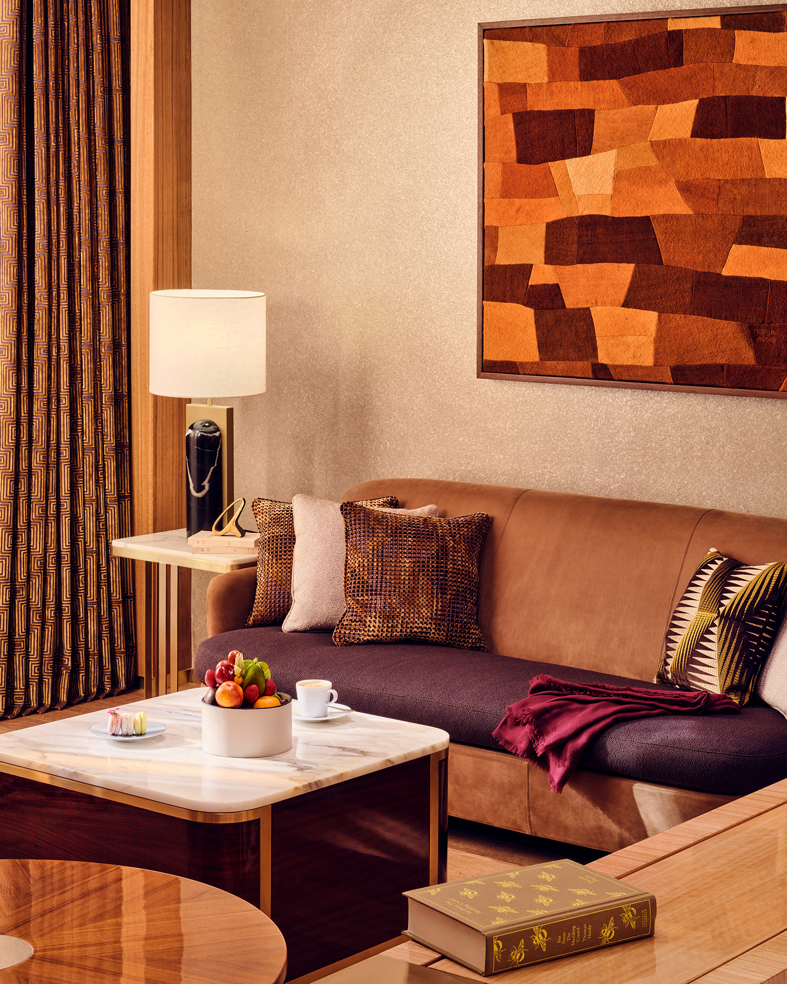 Close up of the details in a suite at Royal Mansour Casablanca featuring a mid-century style sofa with patterned cushions, marble coffee table with fruit bowl and artwork behind