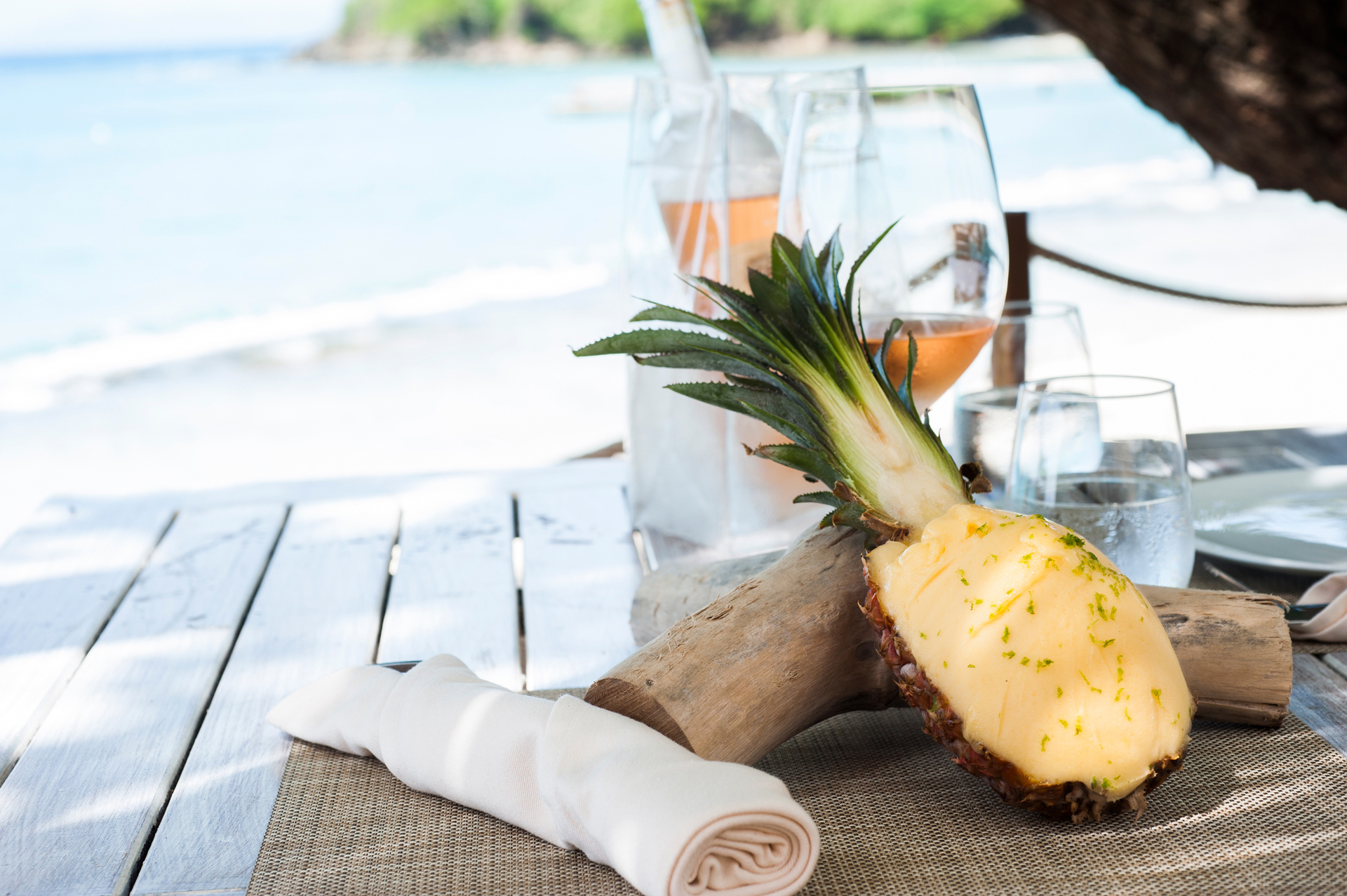 A cut pineapple and glasses on a wooden table