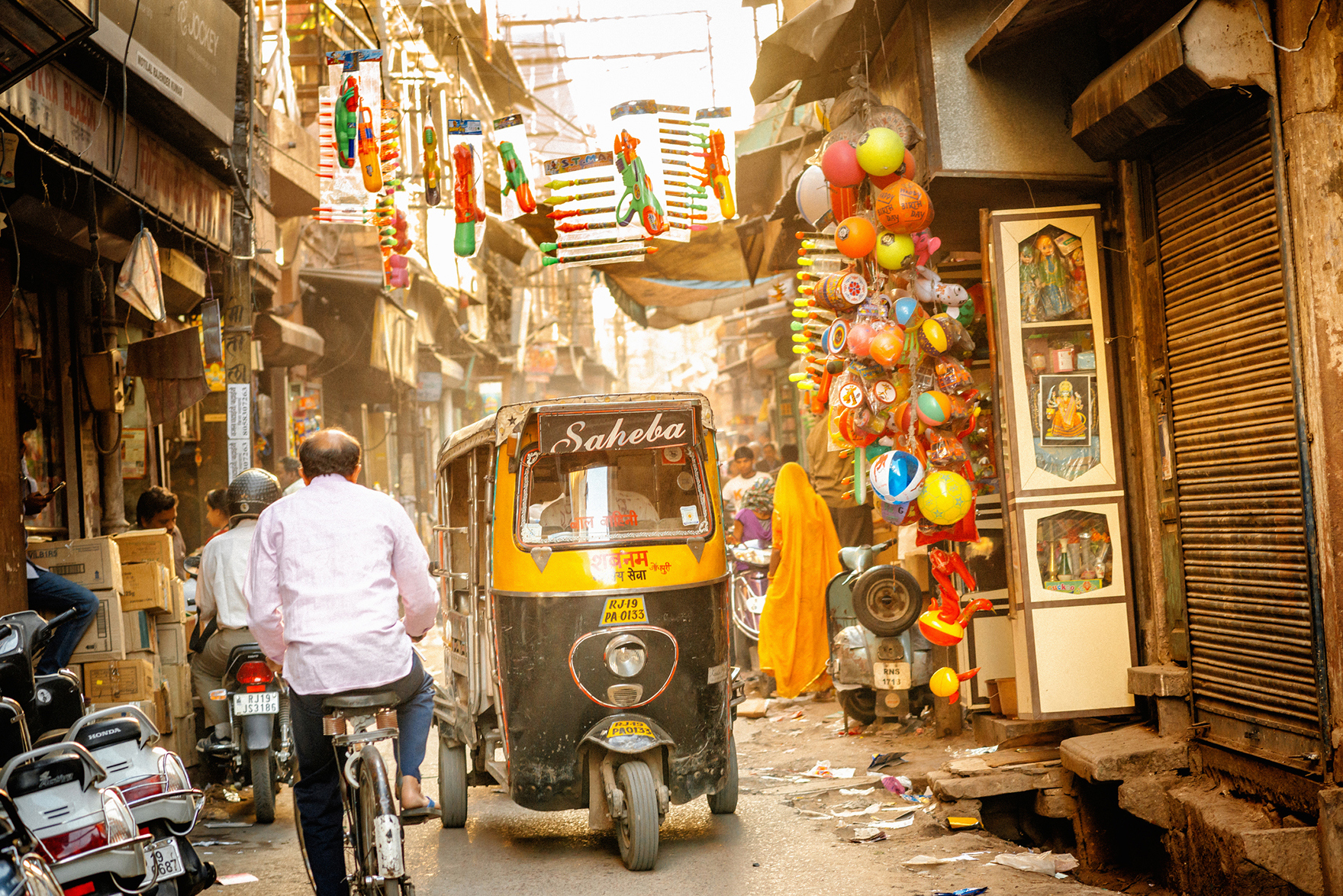 Tuktuk parked in a side street in Delhi with man on bike riding past