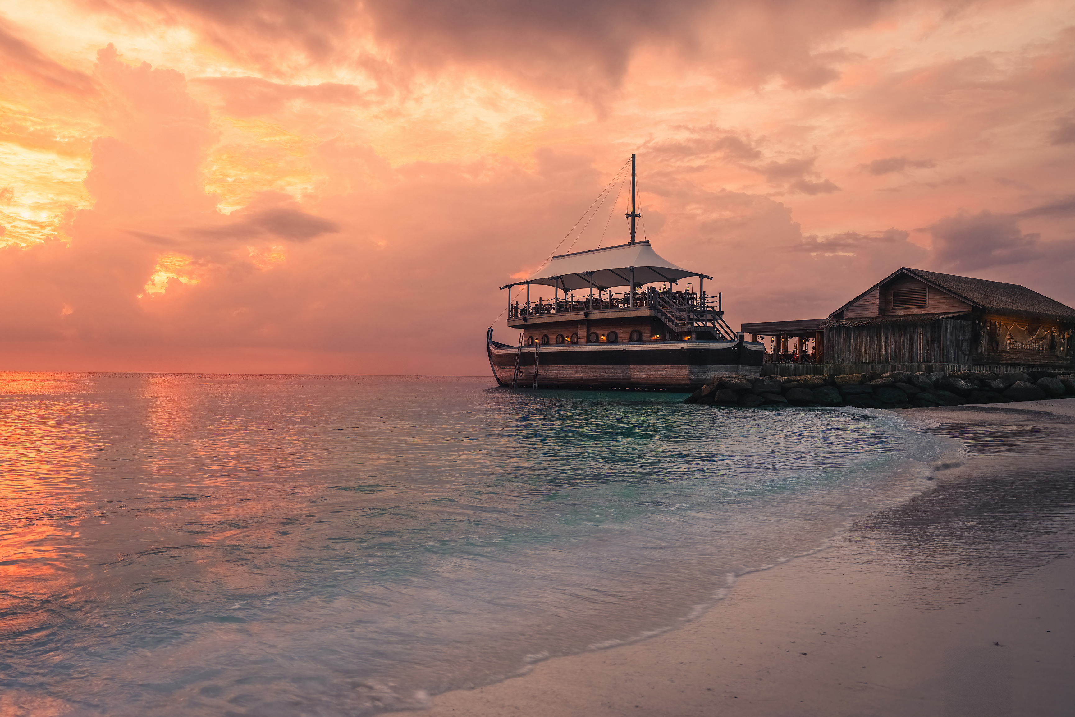InterContinental Maldives traditional boat Sunset Bar at sunset with serene ocean and vibrant sky.