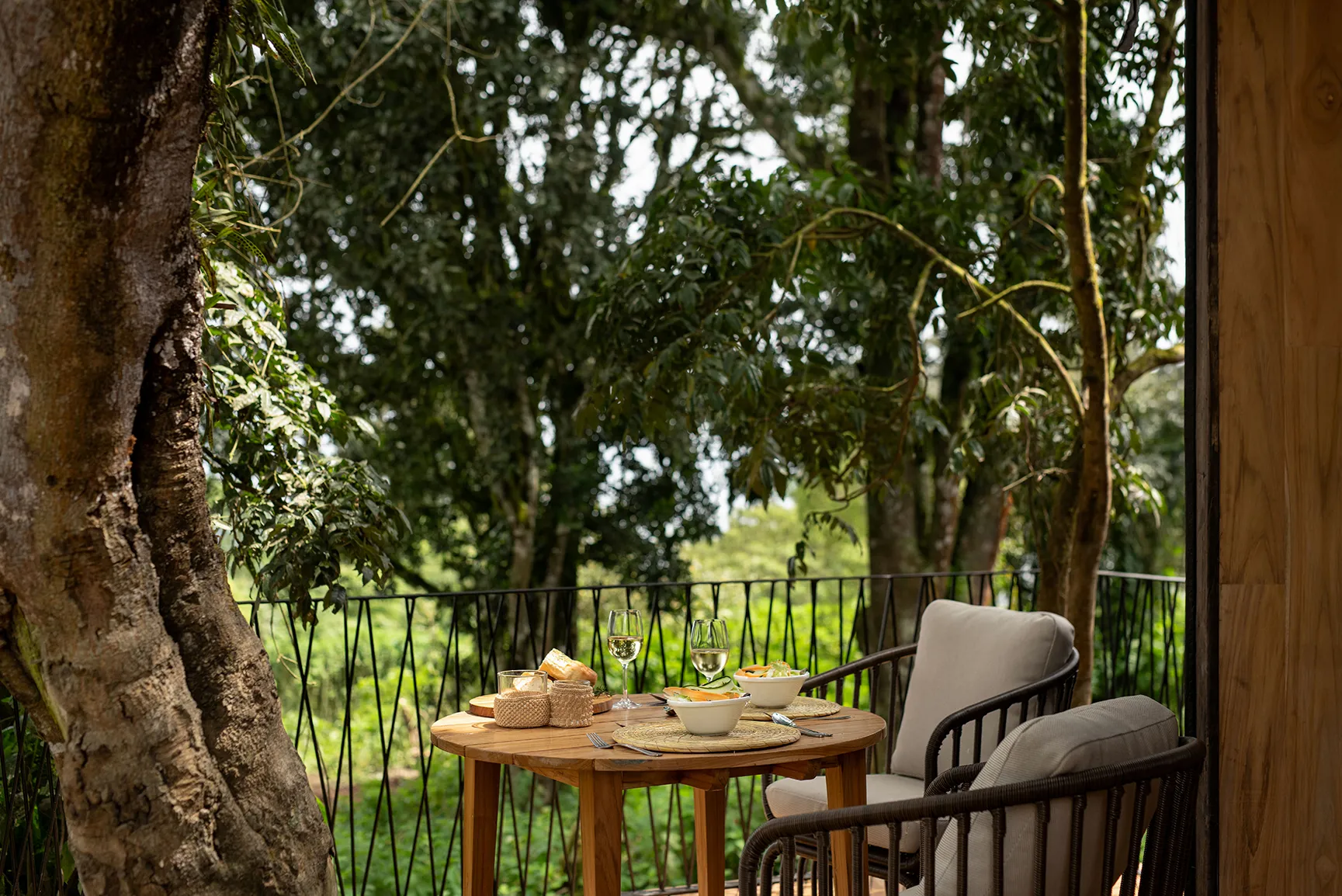 Intimate outdoor dining table set for two surrounded by lush forest greenery