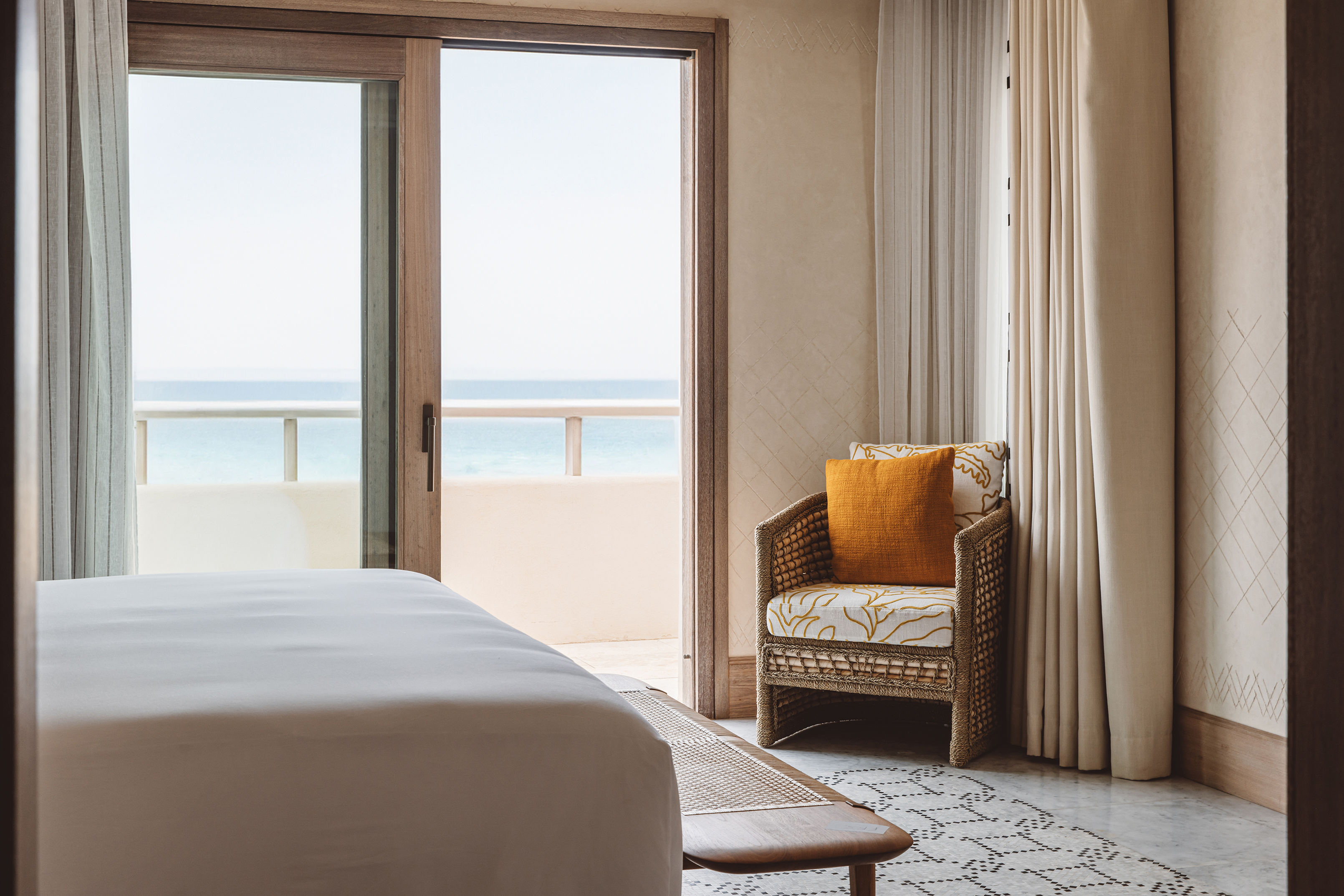 A comfy corner of a suite at Royal Mansour Tamuda Bay featuring a patterned chair and views of the sea