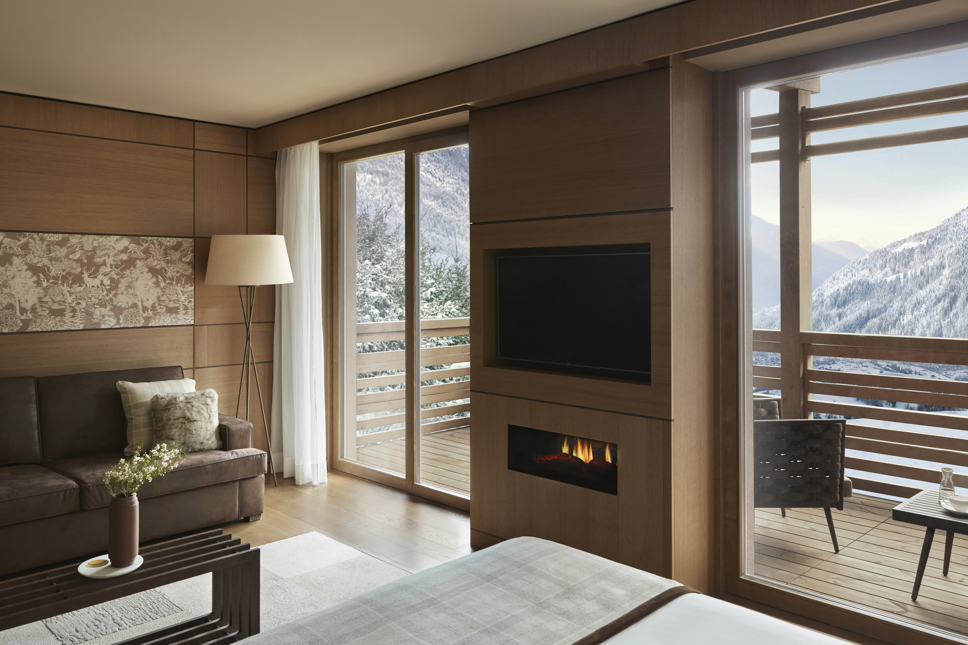 Bedroom of deluxe junior suite with fireplace and balcony with views over snow covered valley