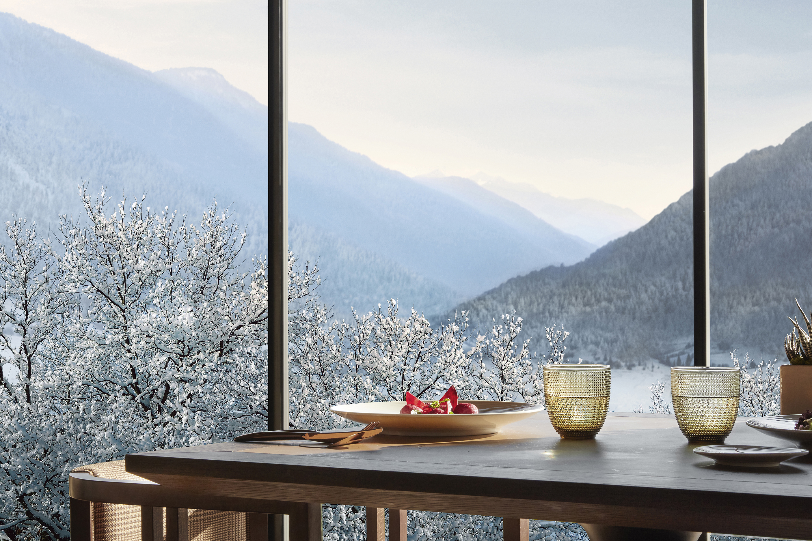 Table of Dolomia restaurant set with dishware and views of snow-coverd valley through windows