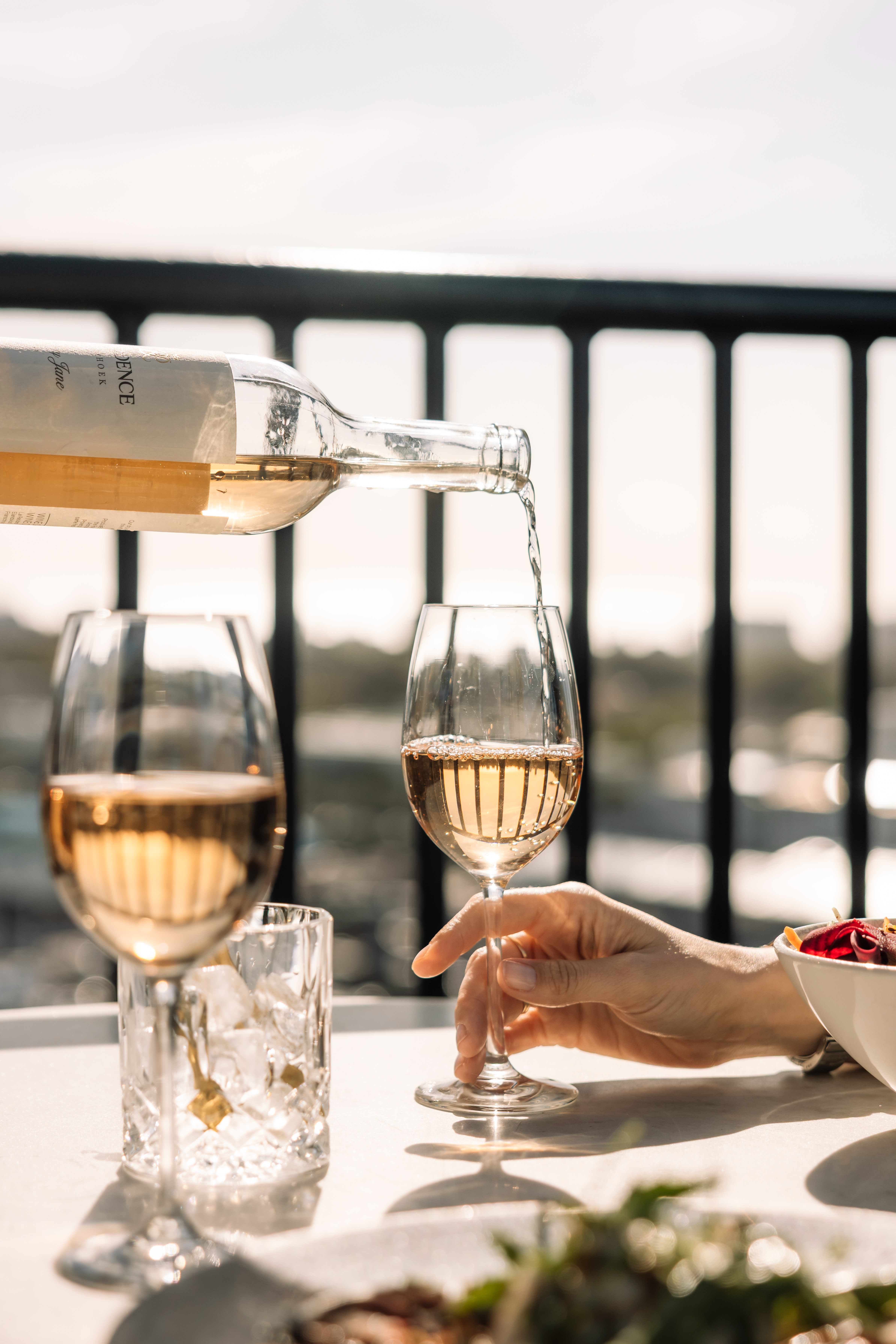 Pouring chilled rosé wine into a glass on a rooftop dining table at The Silo Hotel in Cape Town with scenic city views.