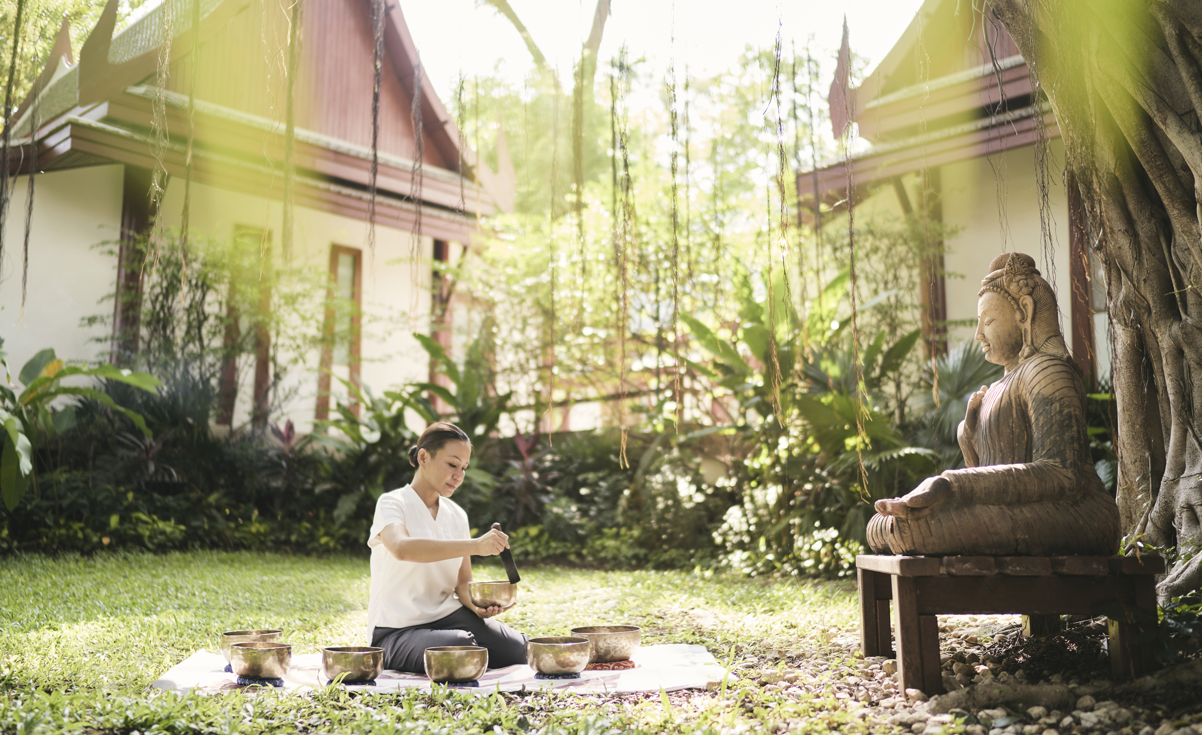 Asia, Thailand, Chiva-Som, woman with Tibetan bowls and Buddha statue
