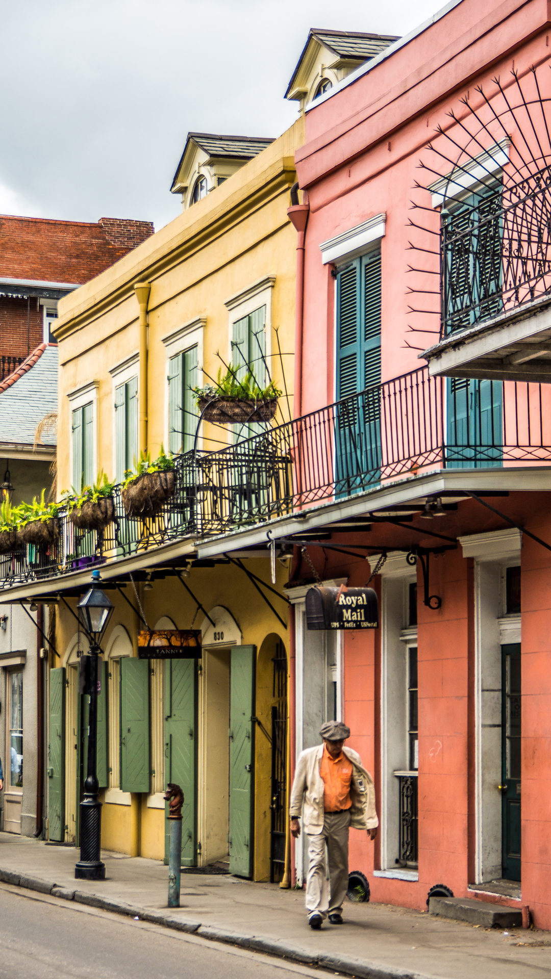 A man walking on a street in front of pastel buildings