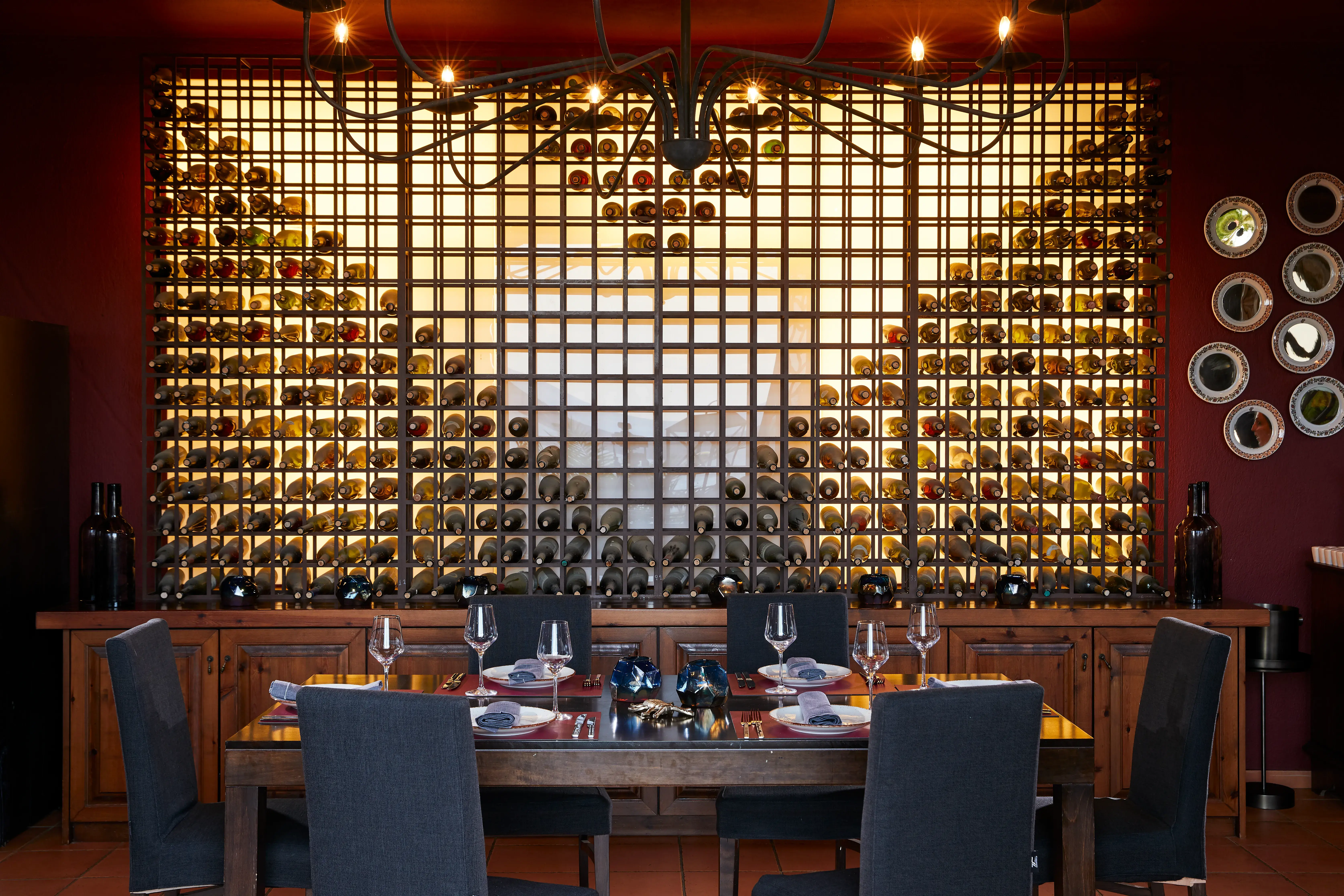 Elegant Vinum Restaurant at Eagles Palace in Greece featuring a dramatic illuminated wine wall and refined dining setting.
