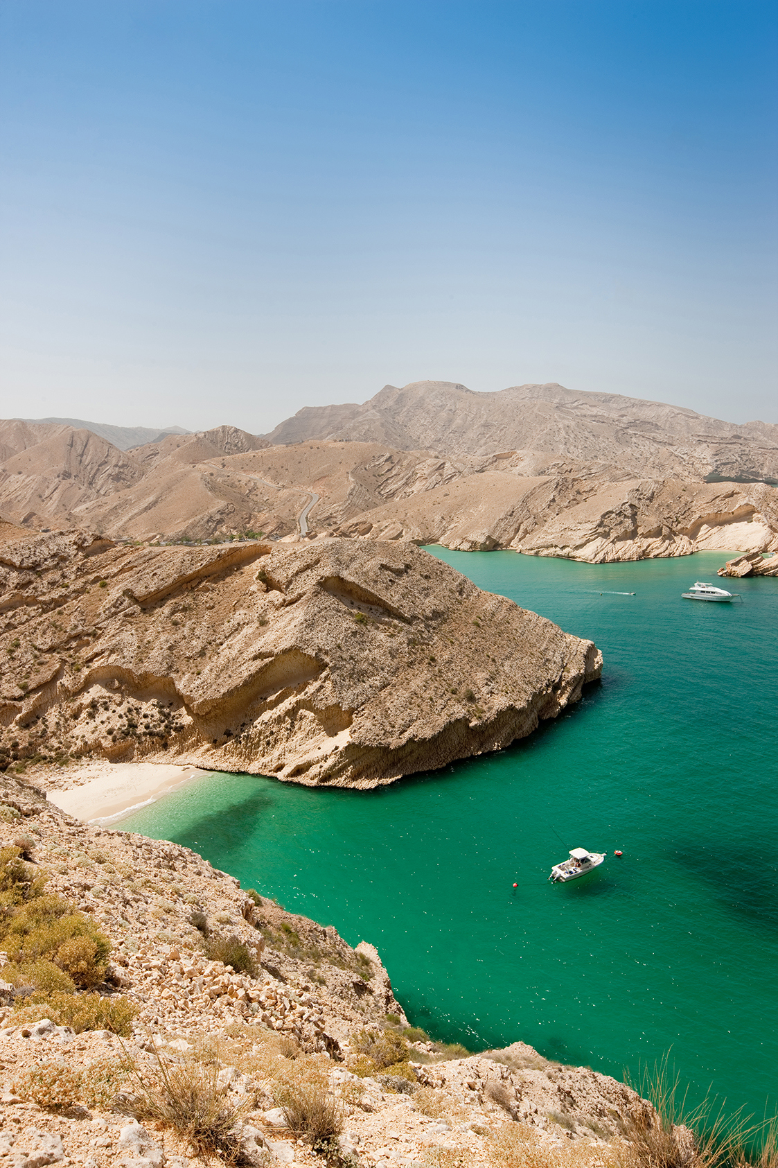 Boat anchored in the green water of a bay in Oman