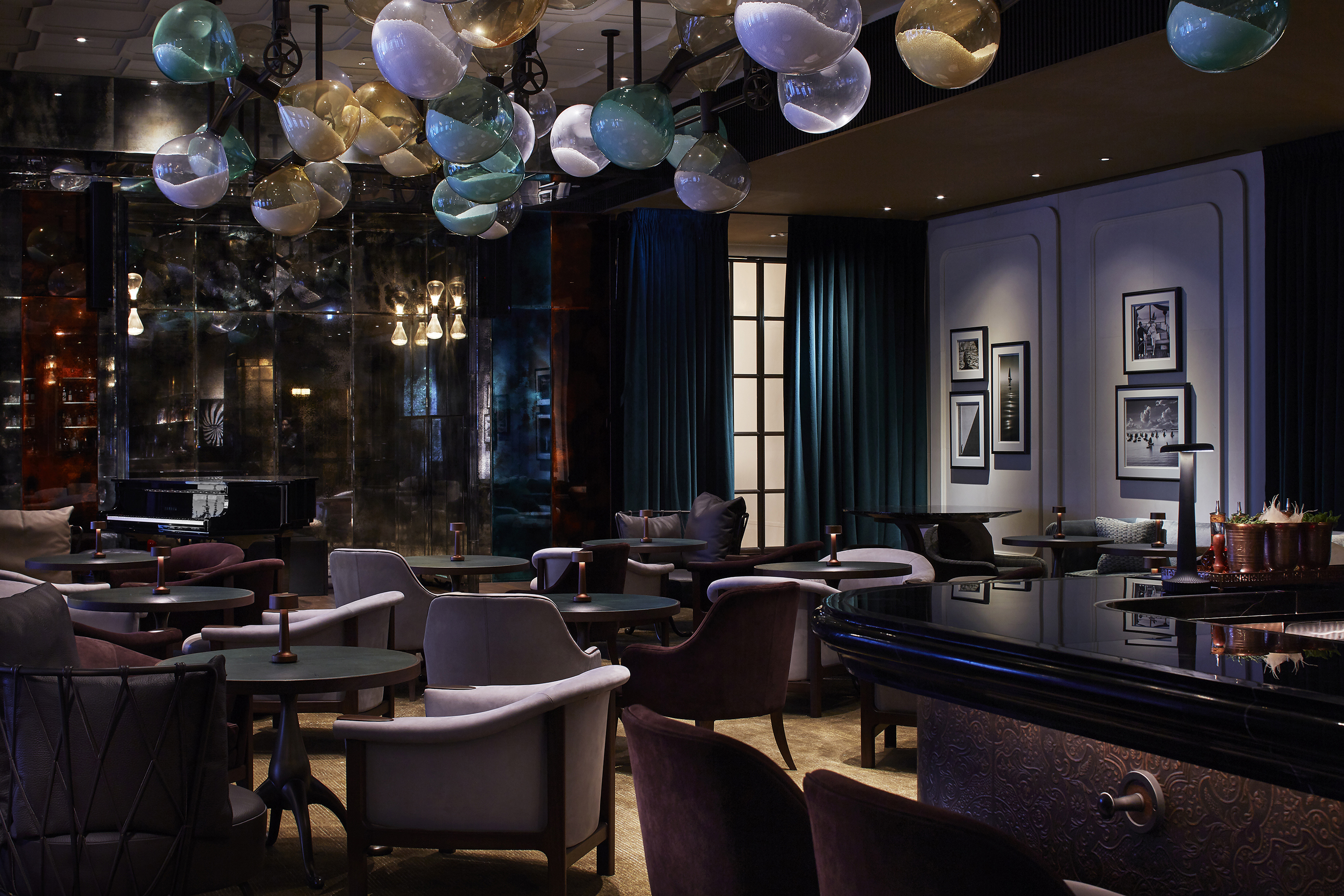 Darkside bar at Rosewood Hong Kong featuring comfy furniture and a statement light fixture with moody dark lighting