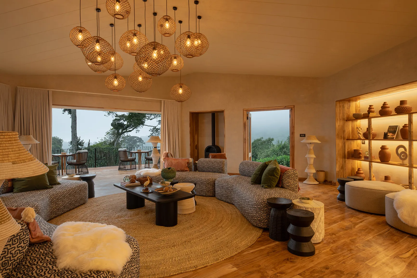 Spacious lodge lounge with curved sofas, woven pendant lights, and forest-view terrace