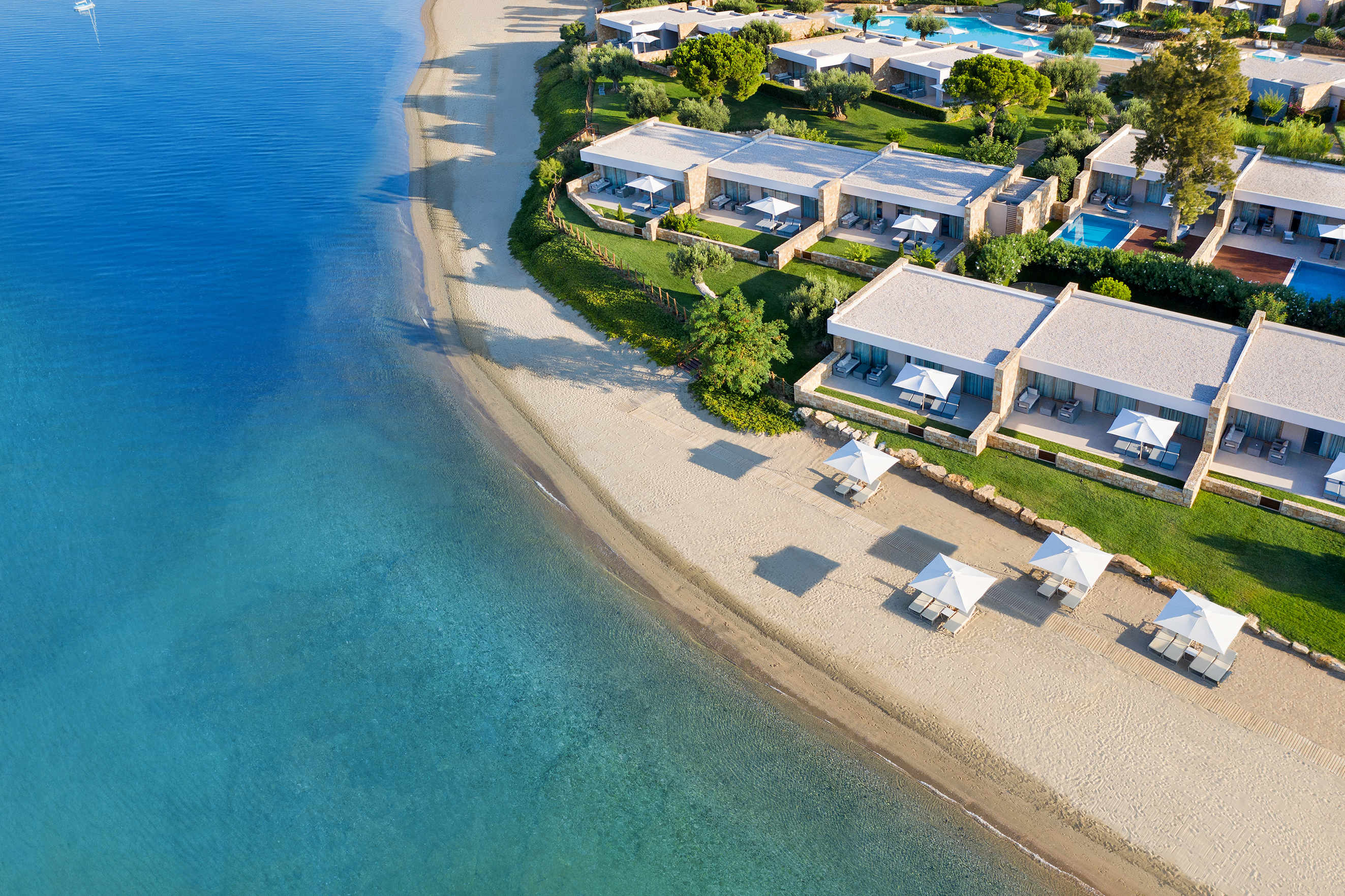 A birds eye view of suites lining the beach with sun loungers