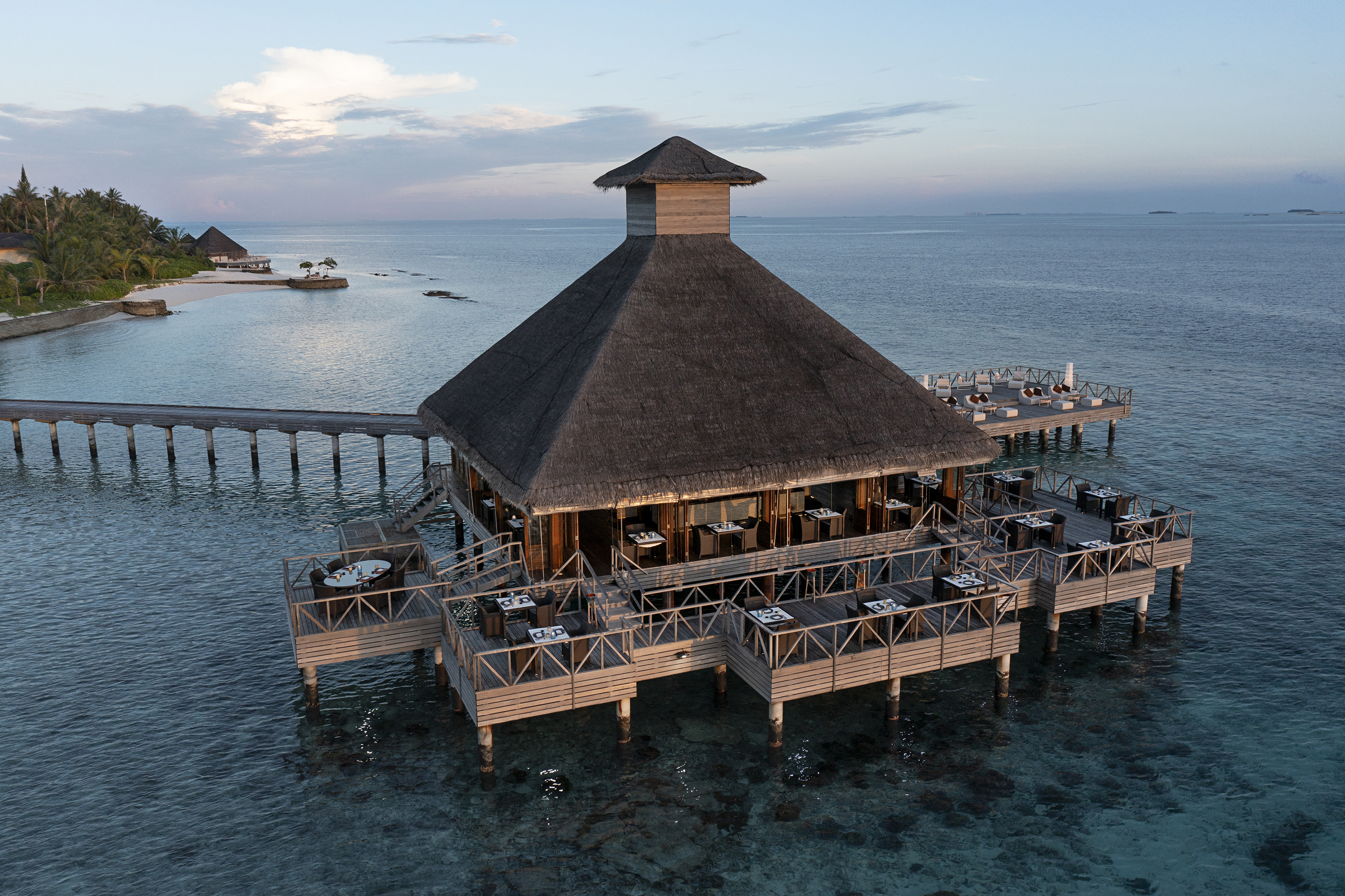 The thatched pavilion exterior of Salt at Huvafen Fushi with tables on the outside decking