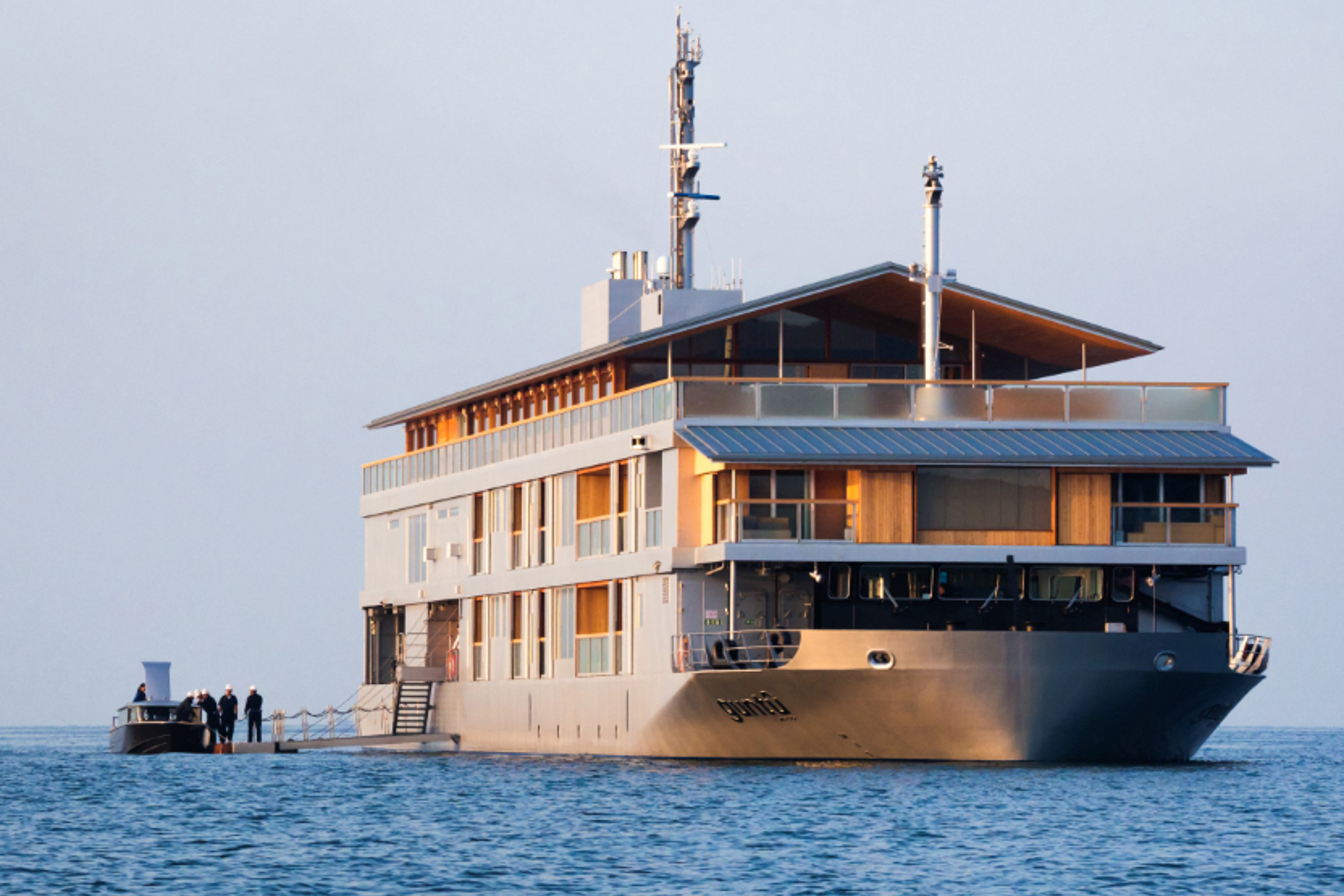 Guntu boat anchored while people board from a small transport boat