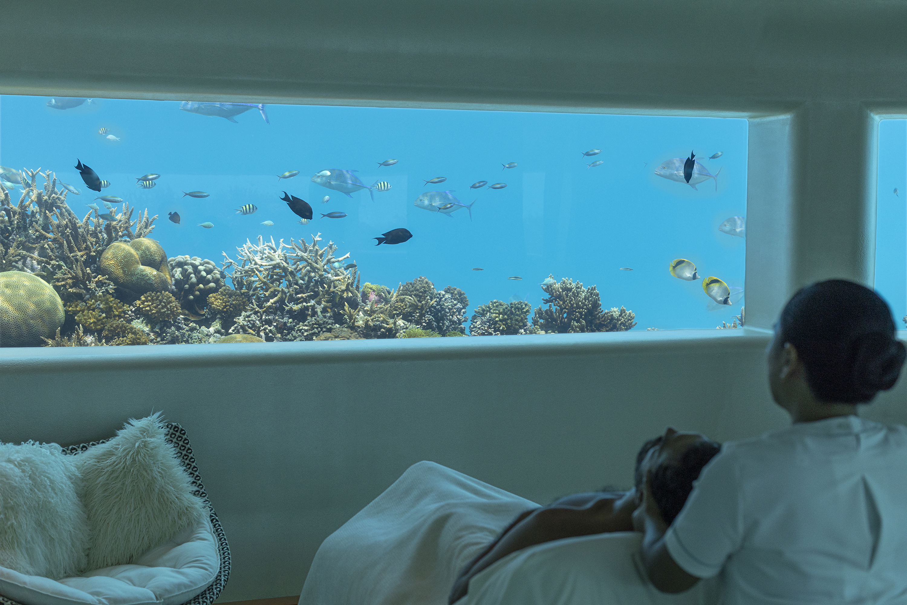 A massage therapist giving a guest a head massage in the underwater spa at Huvafen Fushi