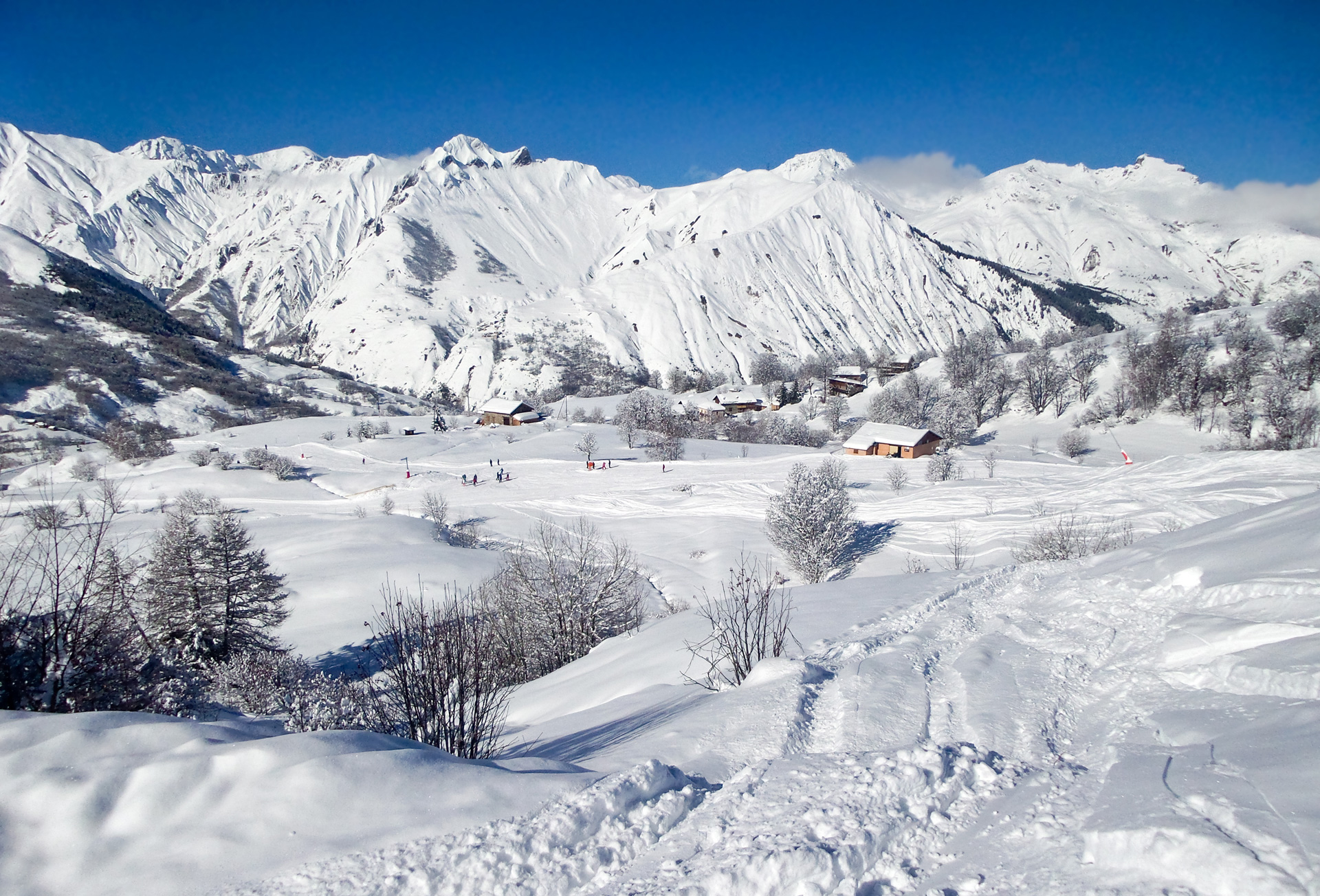 A white snowy landscape with wooden chalets dotted around