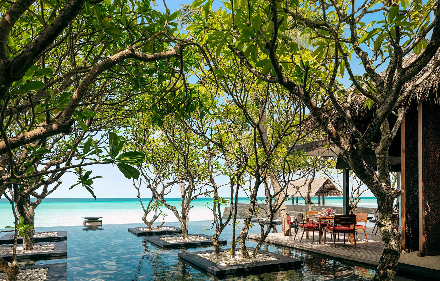An outdoor dining table beside a water feature with a sea view at One&Only Reethi Rah, Maldives