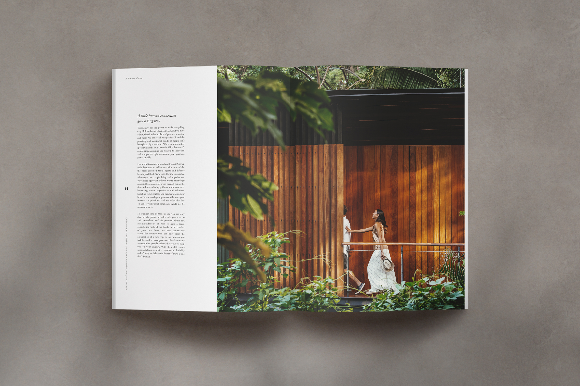 A book is spread open on a grey surface, its pages showing a photo of a couple on holiday and accompanying words