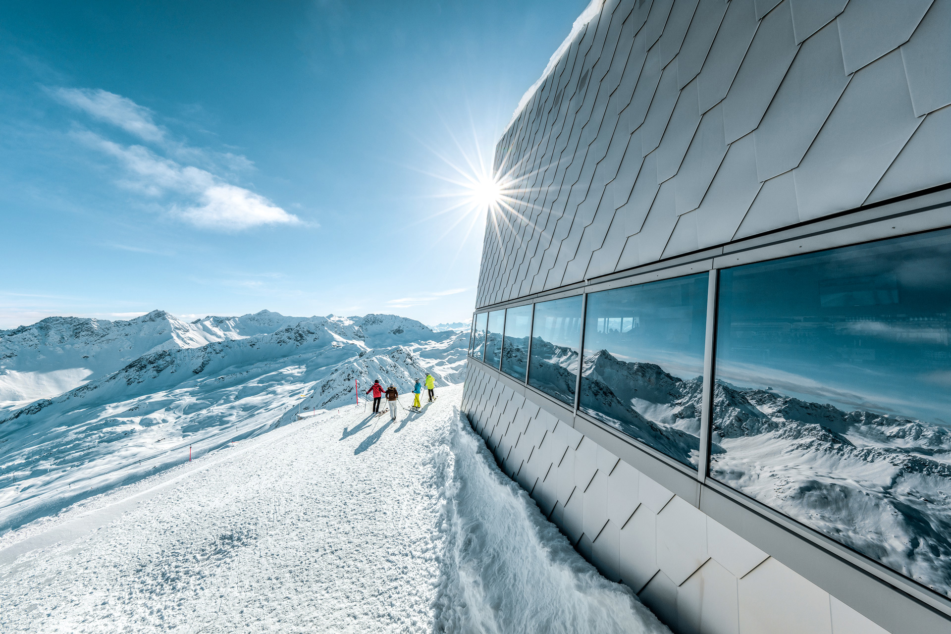 Looking along the side of a sleek modern building on the top of a snowy mountain