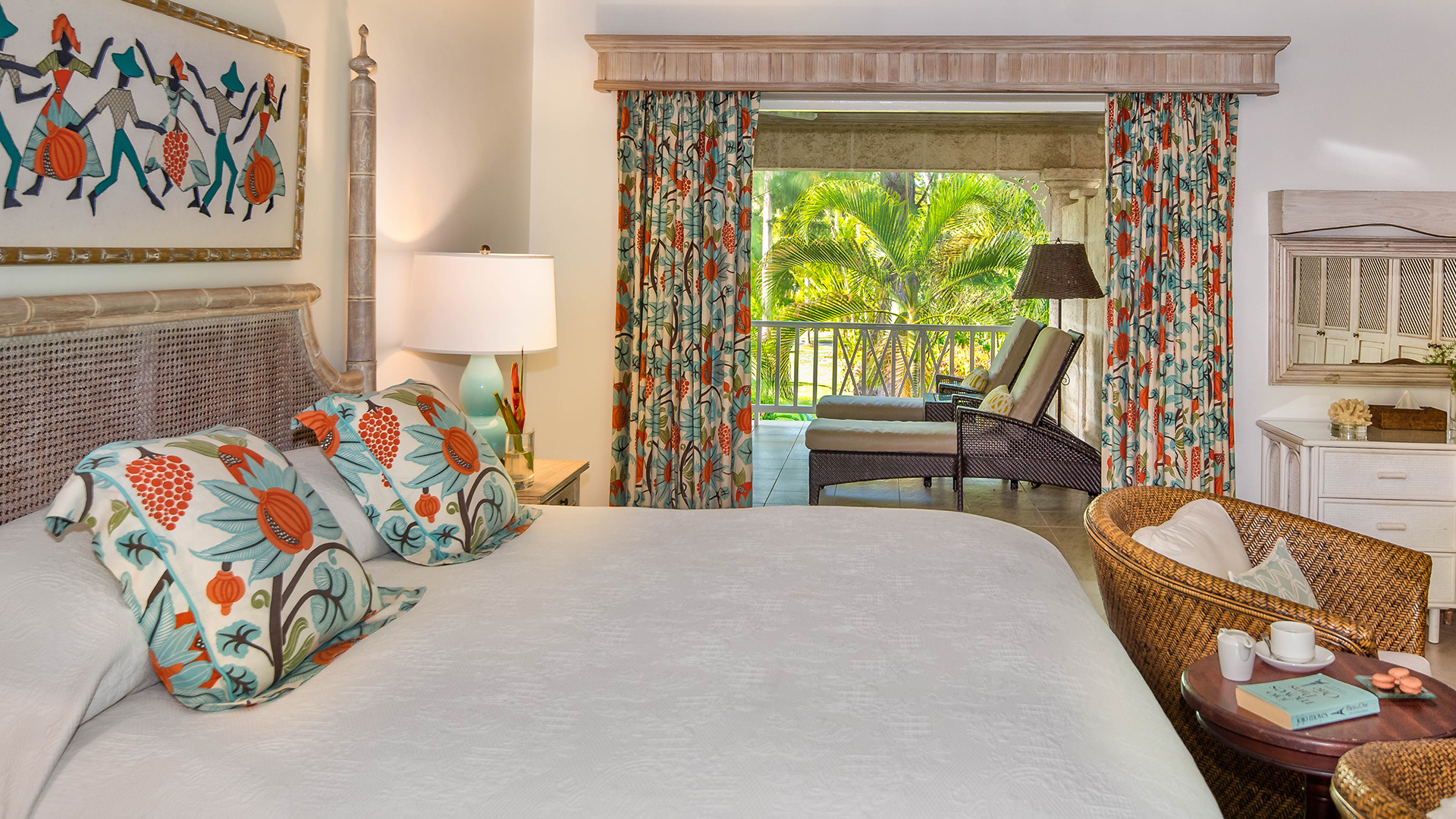 Garden room bed with orange and blue cushion and terrace with loungers at Coral Reef Club