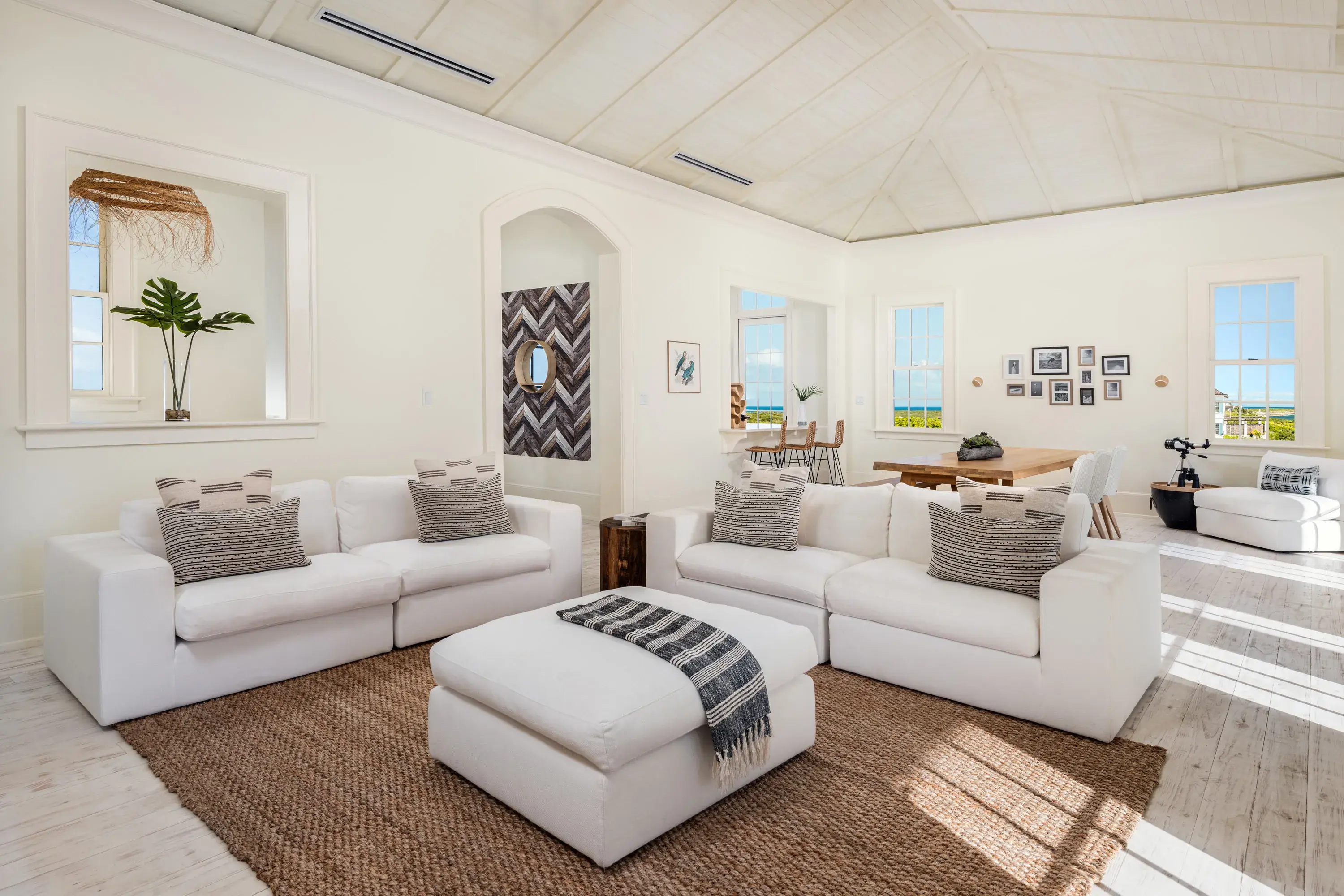 Neptune Villa living room at Ambergris Cay in Turks & Caicos featuring pale furniture with Caribbean-style decor beneath vaulted ceilings
