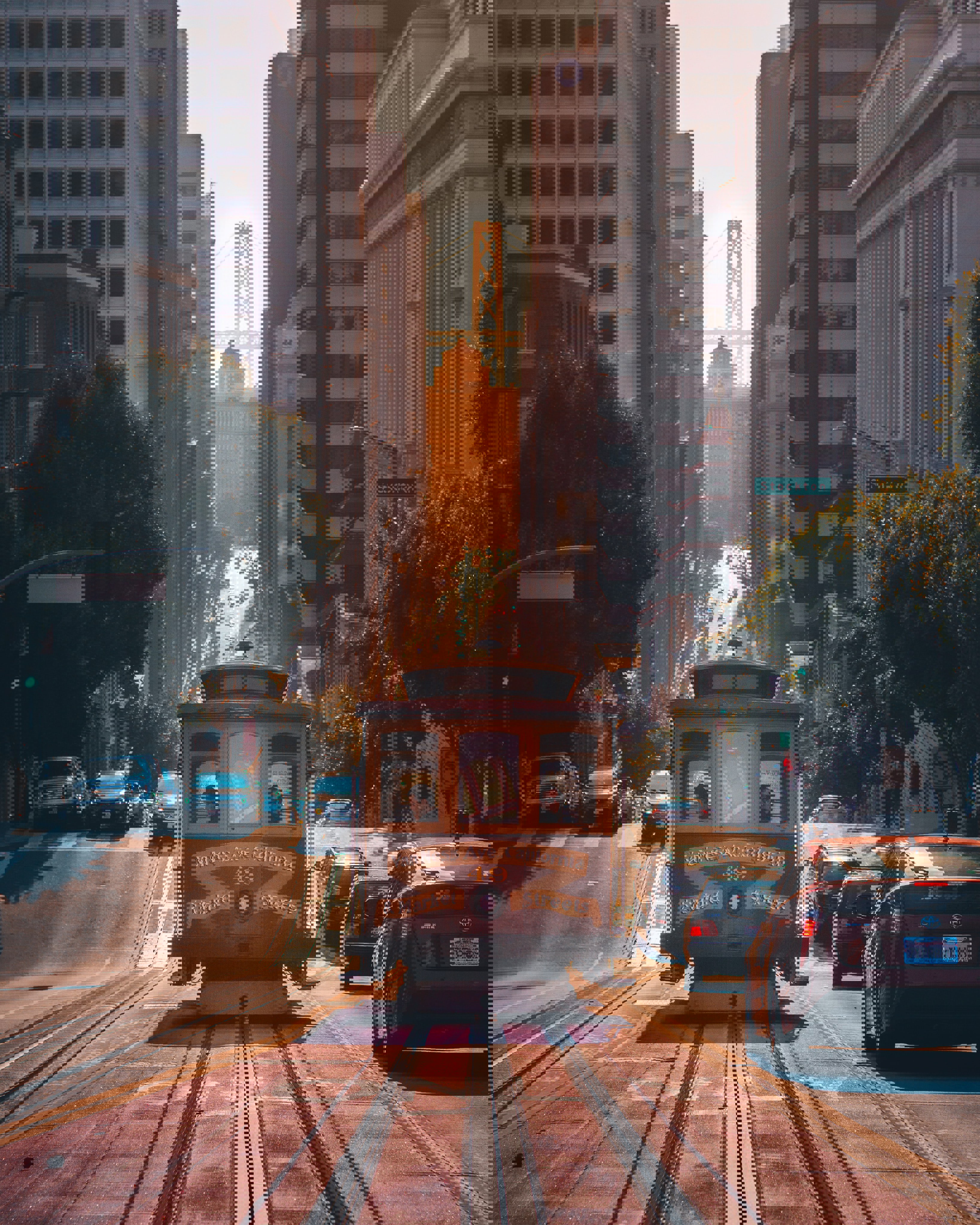 A streetcar with passengers travelling down a steep hill in San Francisco beside cars