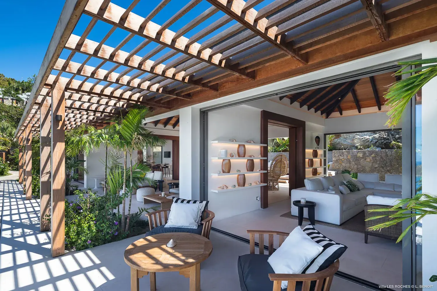 Open‑air lounge at Les Roches Villa in St Barths with pergola shade, modern outdoor seating and lush tropical surroundings.