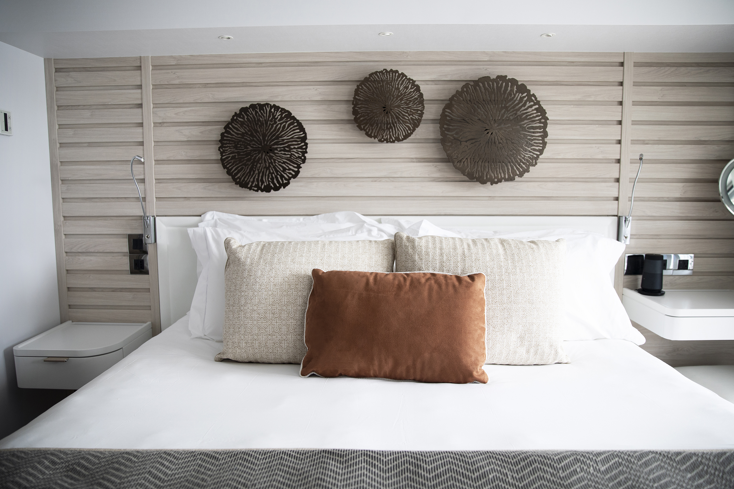 A relaxing red in a suite aboard PONANT Le Dumont d'Urville featuring neutral decor with coral-like artwork.