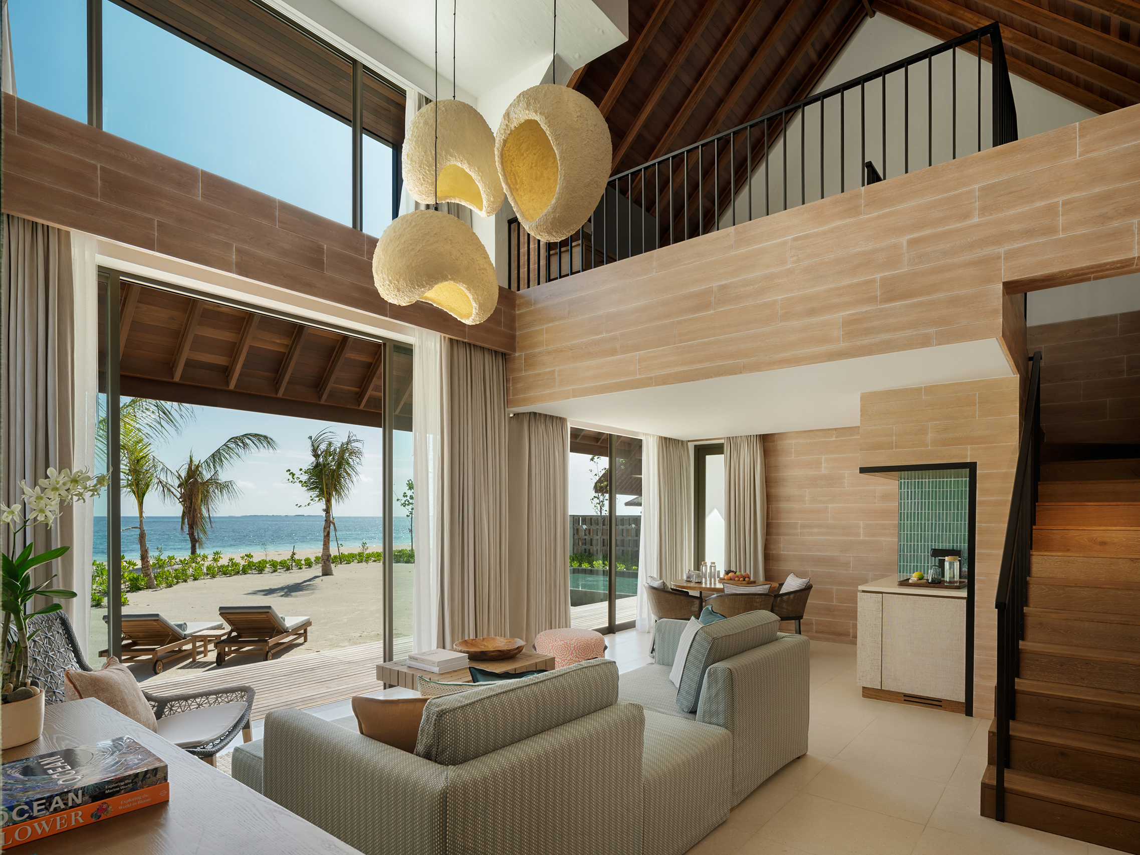 Lounge with sculptural lights and outside terrace with lounger in a Beach Retreat at Six Senses Kanuhura