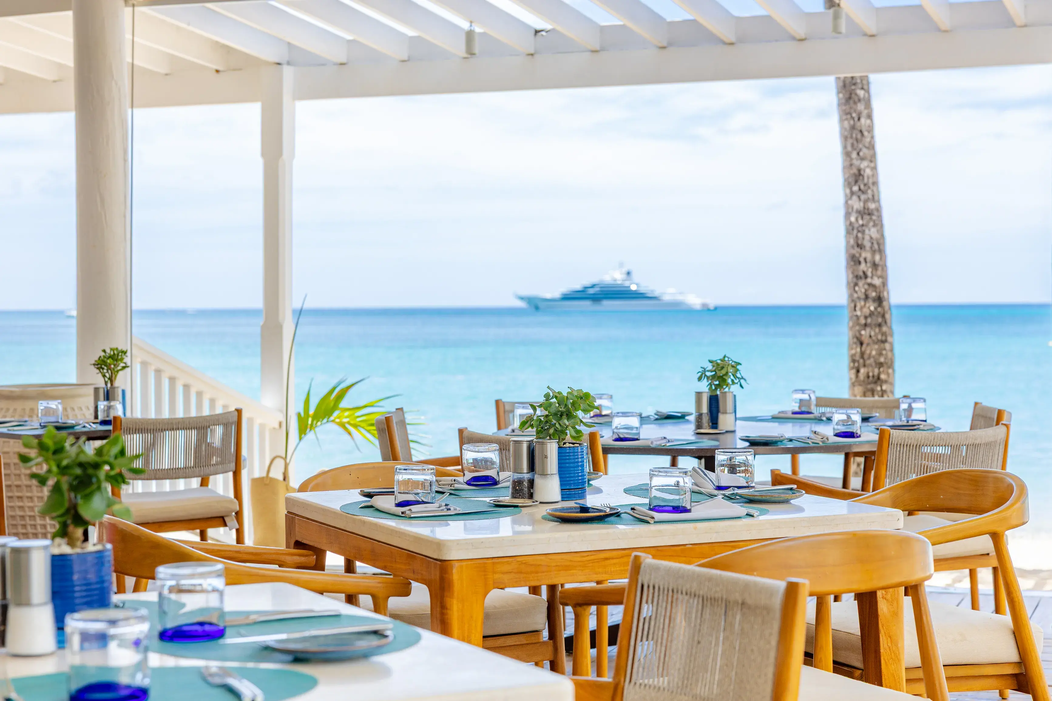 Tables with blue glasses set for dinner at Indigo by the Sea Restaurant at Carlisle Bay, Antigua