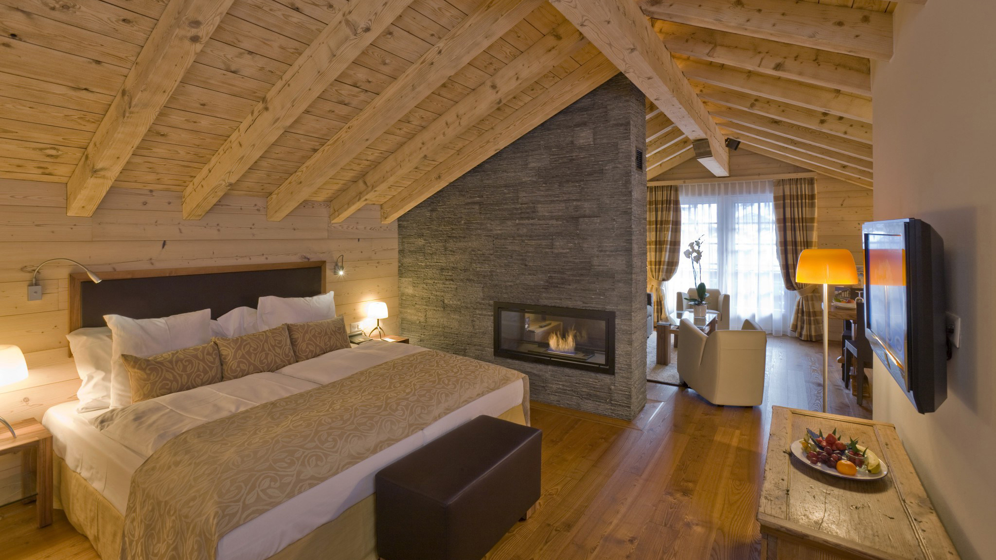 A cosy vaulted bedroom with comfy furniture and stone fireplace