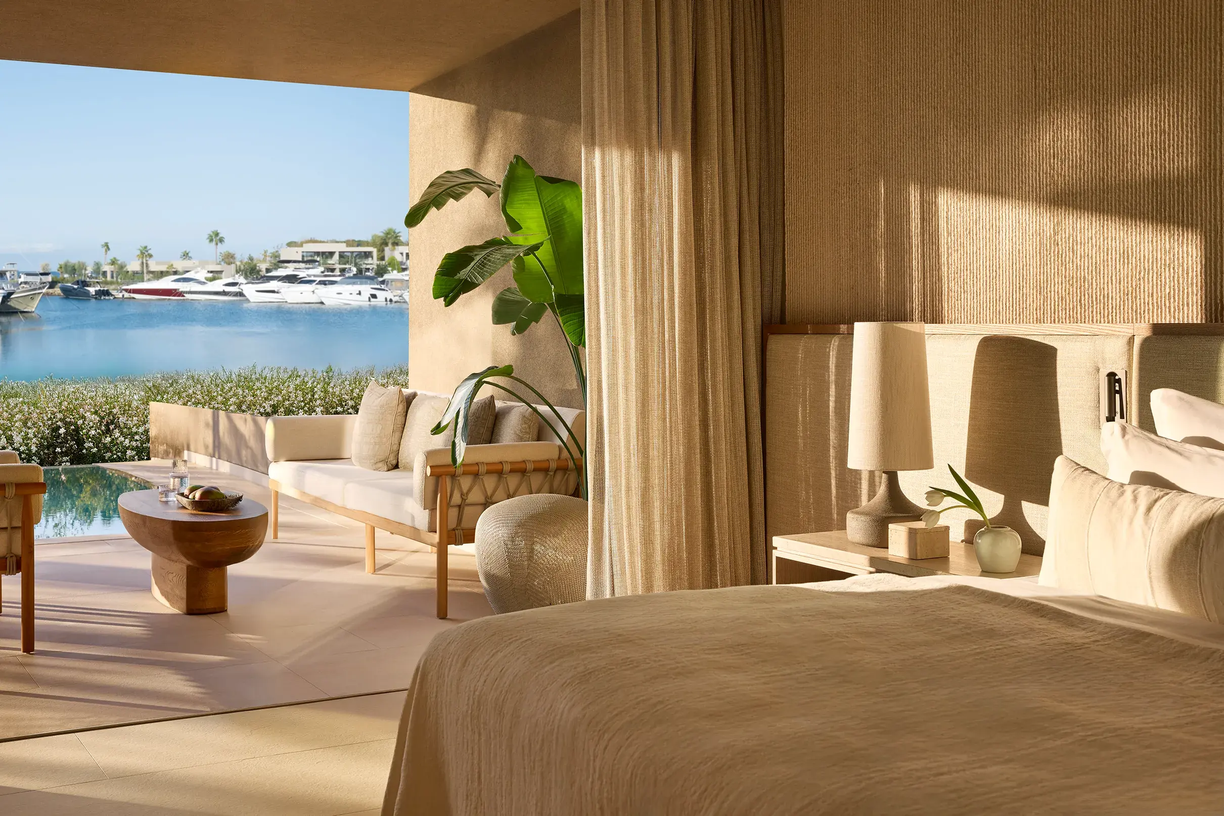 Luxury marina‑view bedroom in a three bedroom residence at Sani Asterias in Halkidiki featuring elegant natural décor and a private terrace overlooking yachts and calm waters.