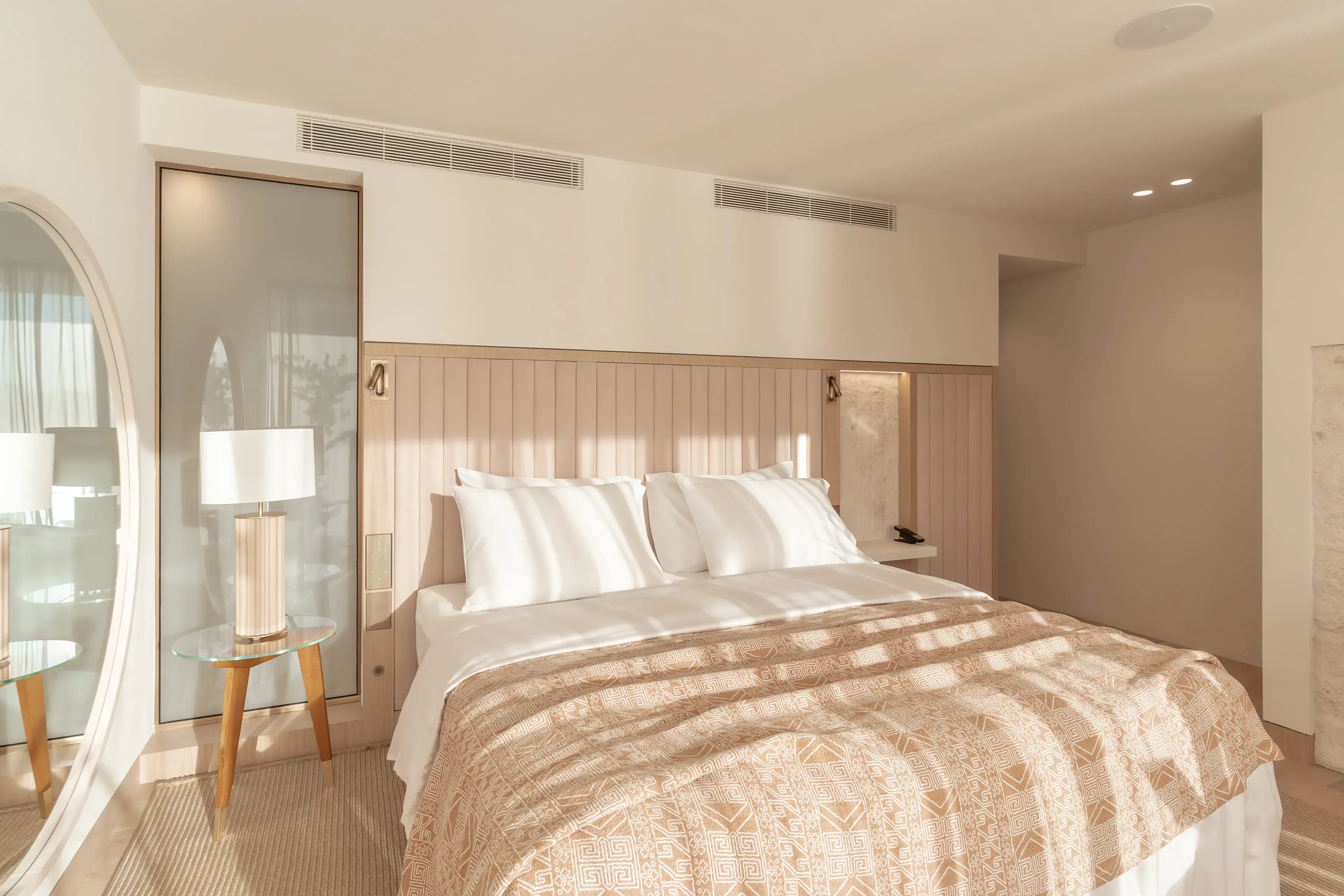 Bedroom of Beleca Suite at Villa Dubrovnik in Croatia with a large bed, bedside lamp and mirror decorated in warm pale colours