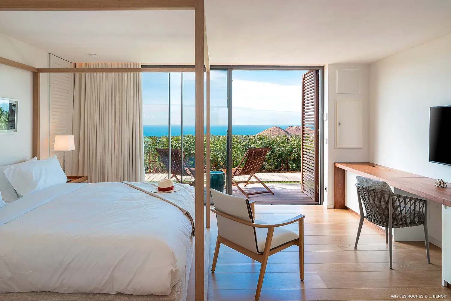 Elegant ocean‑view bedroom at Les Roches Villa in St Barths with modern décor, sliding glass doors and private terrace overlooking the Caribbean Sea.