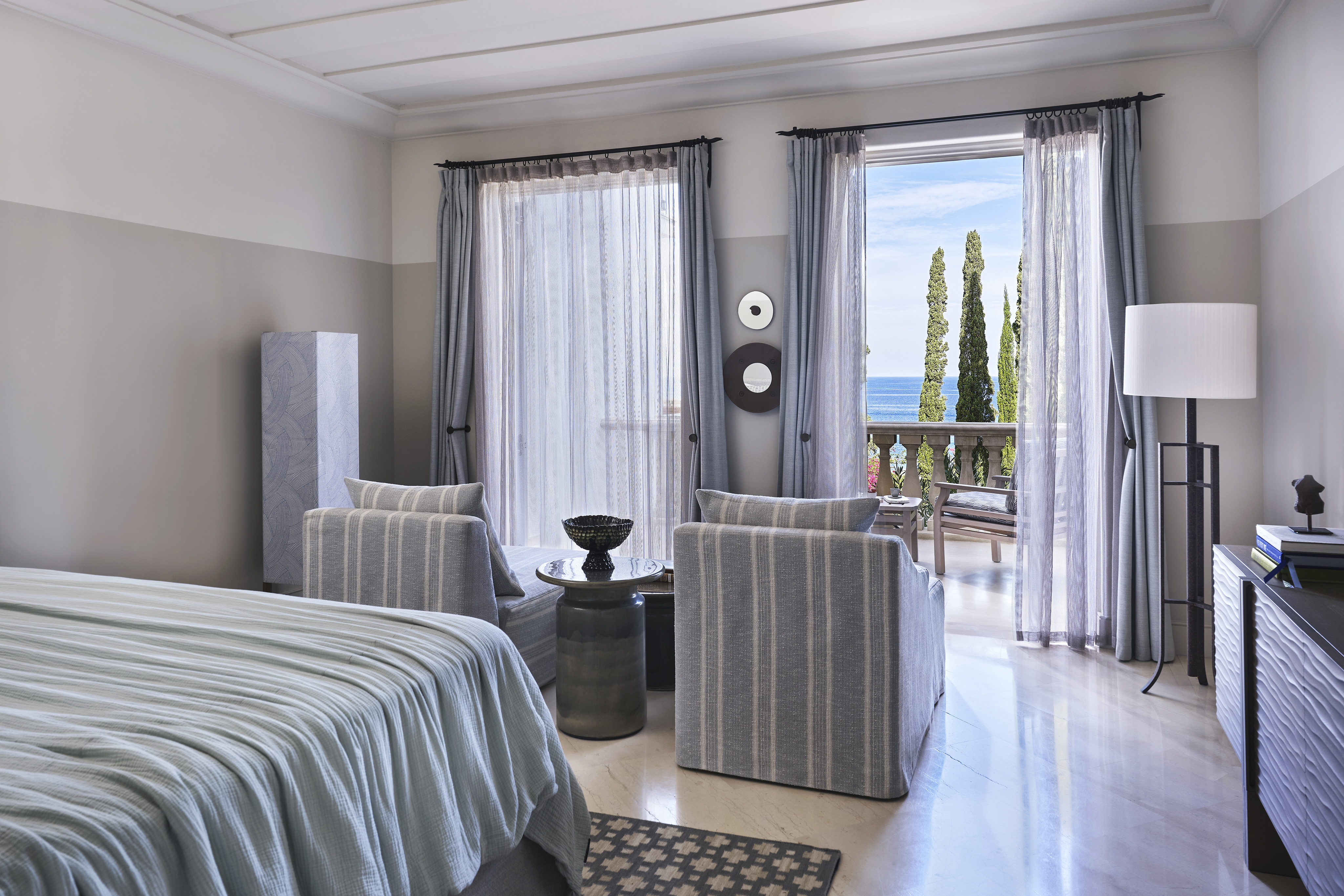 A one bedroom suite at Anassa in Cyprus featuring blue coastal furniture facing two balcony doors overlooking the sea