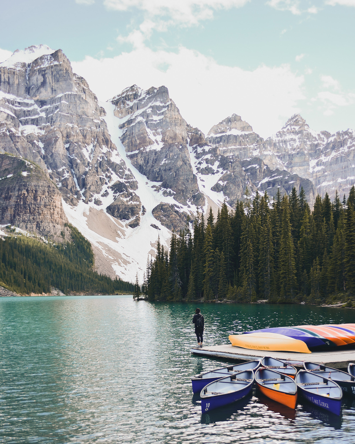 Person stood on jetty with colourful boats on Lake Louise