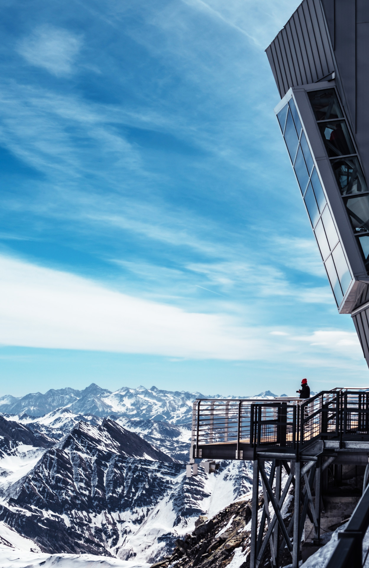 A person standing on a ski lift viewing platform looking out to the mountains