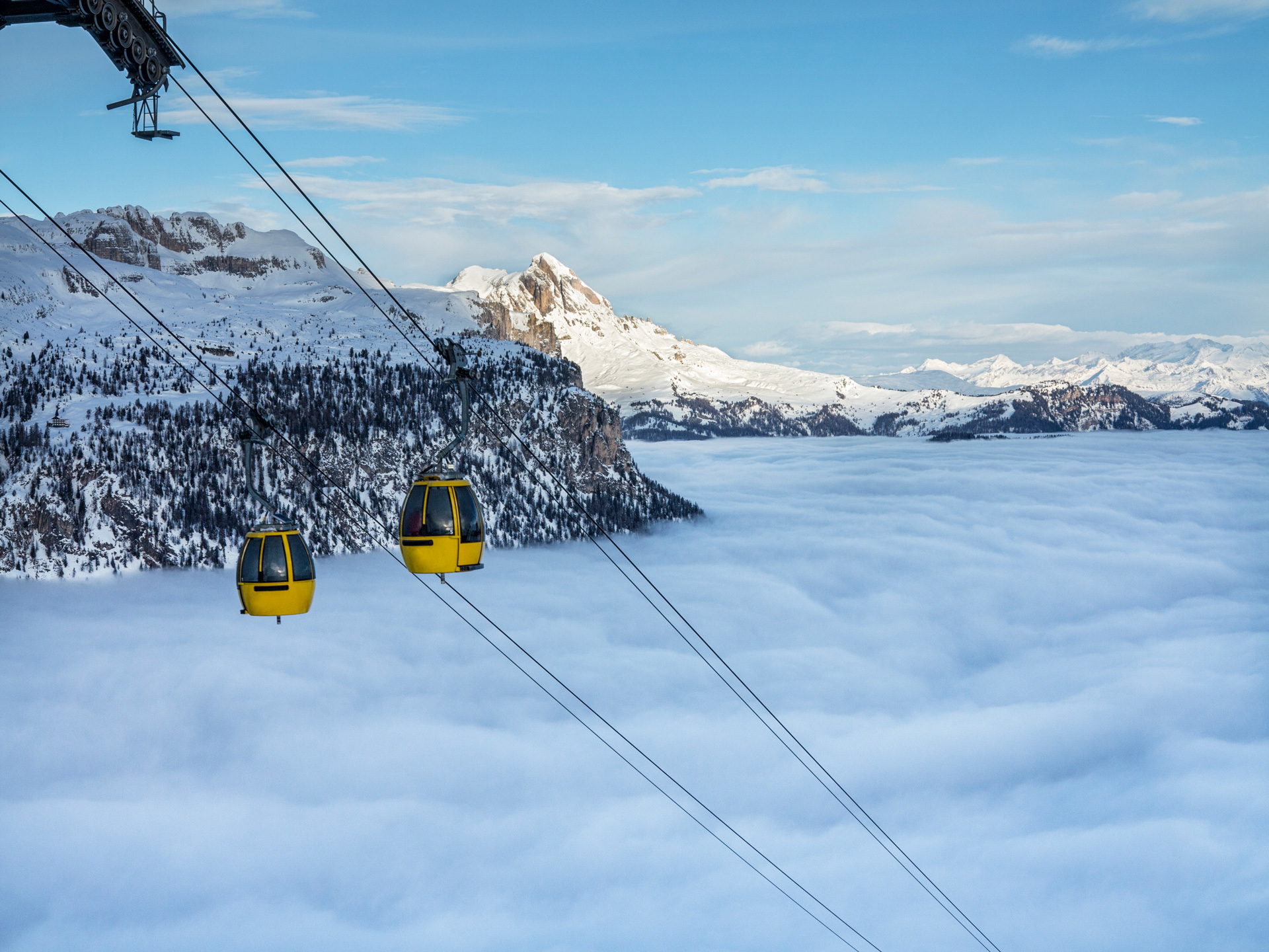 Two yellow ski lifts above the clouds
