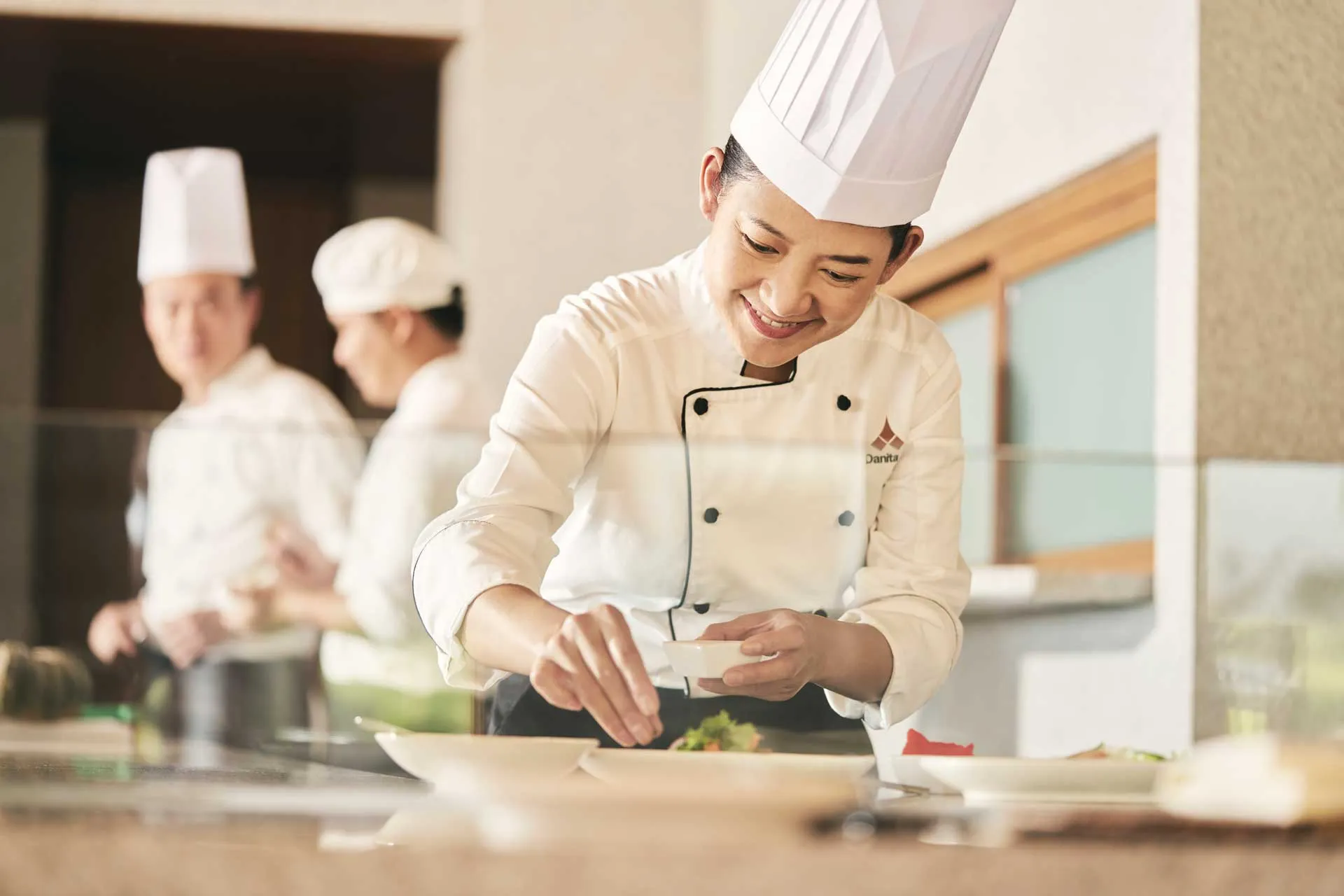 Chef at Chiva Som carefully plating a fresh, healthy dish in a bright, modern kitchen.