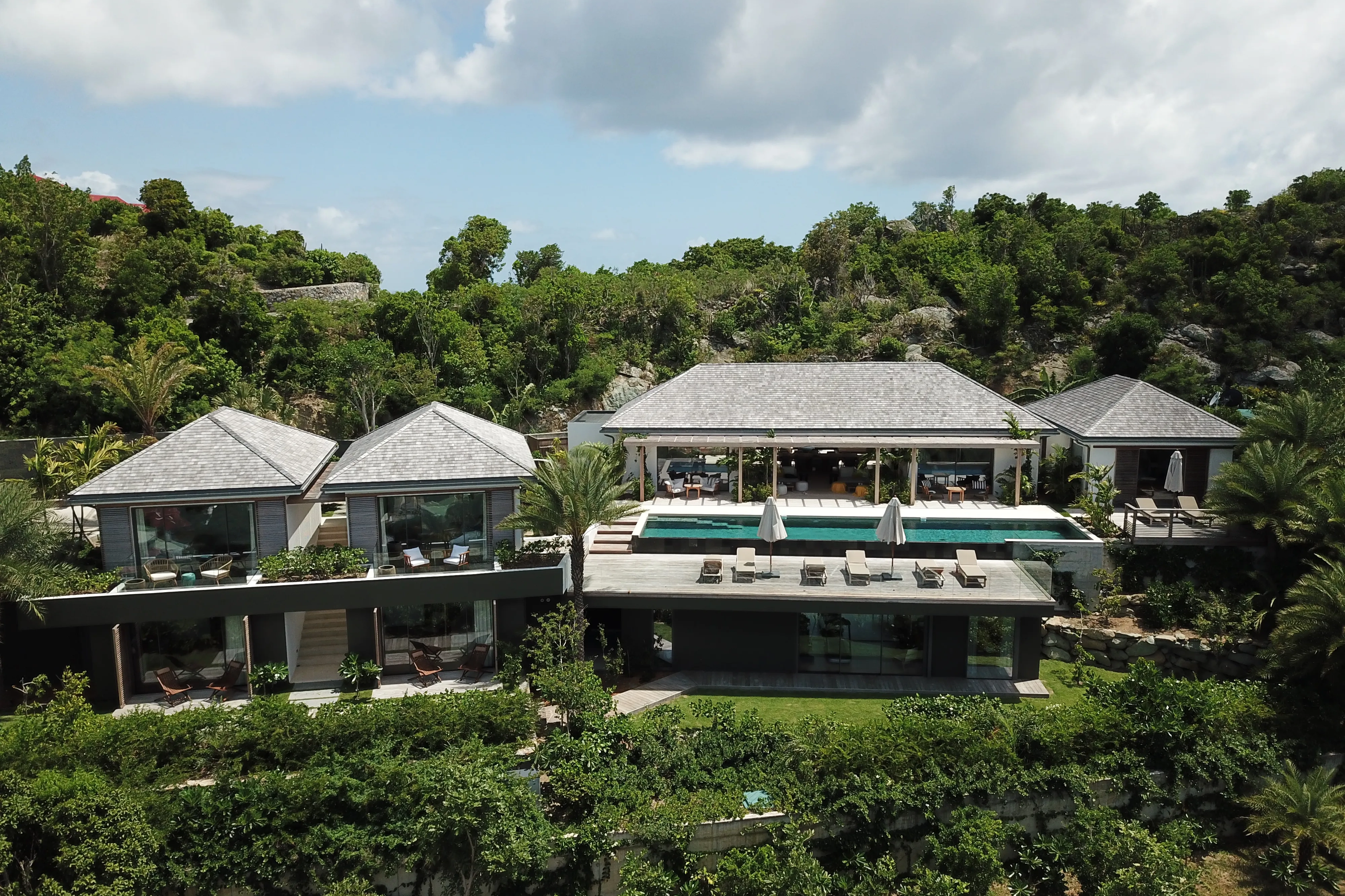Luxury hillside Les Roches Villa in St Barths with modern architecture, infinity pool and lush tropical surroundings.
