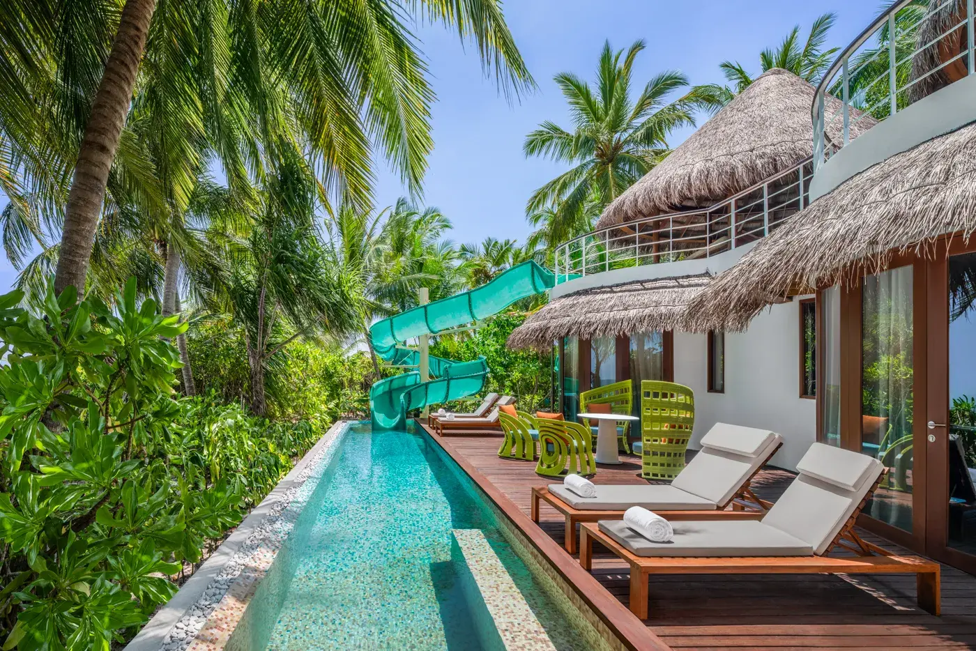 Oasis Beach Two-Bedroom Villa at W Maldives featuring a private swimming pool with waterslide, sun loungers, tropical gardens, and stylish outdoor living spaces surrounded by lush island greenery